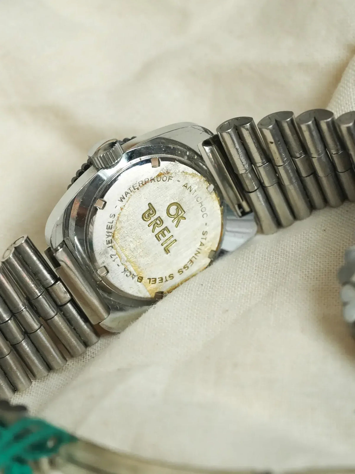 Vintage Breil watch with stainless steel case and bracelet, back view on fabric