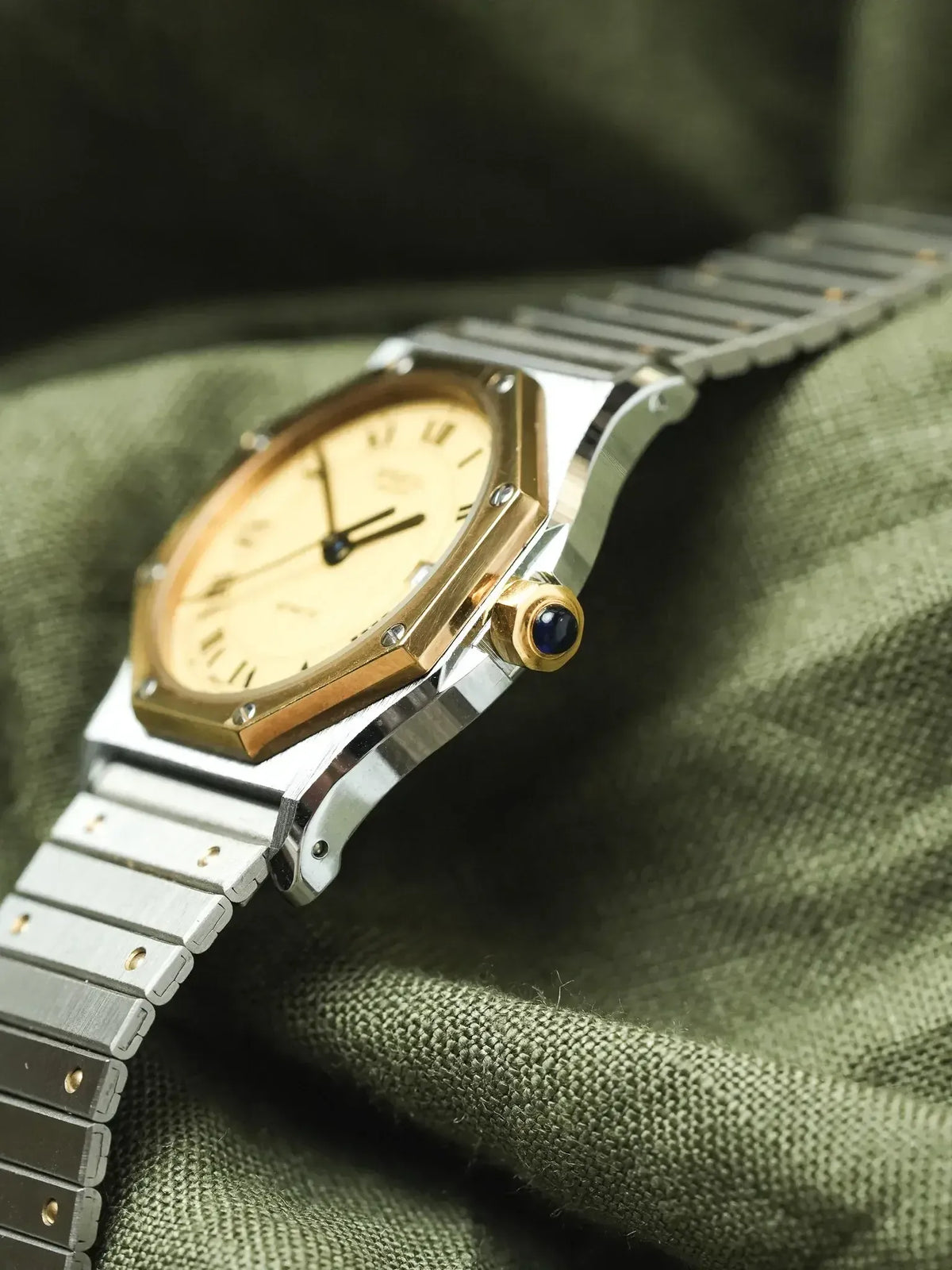 Cartier Santos vintage watch with gold bezel, silver bracelet, cream dial on green fabric