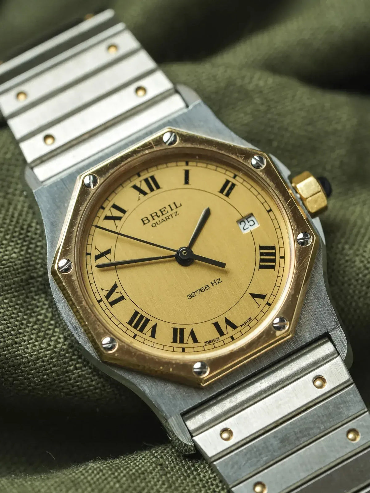 Breil quartz vintage watch with gold dial, Roman numerals, steel bracelet on green fabric