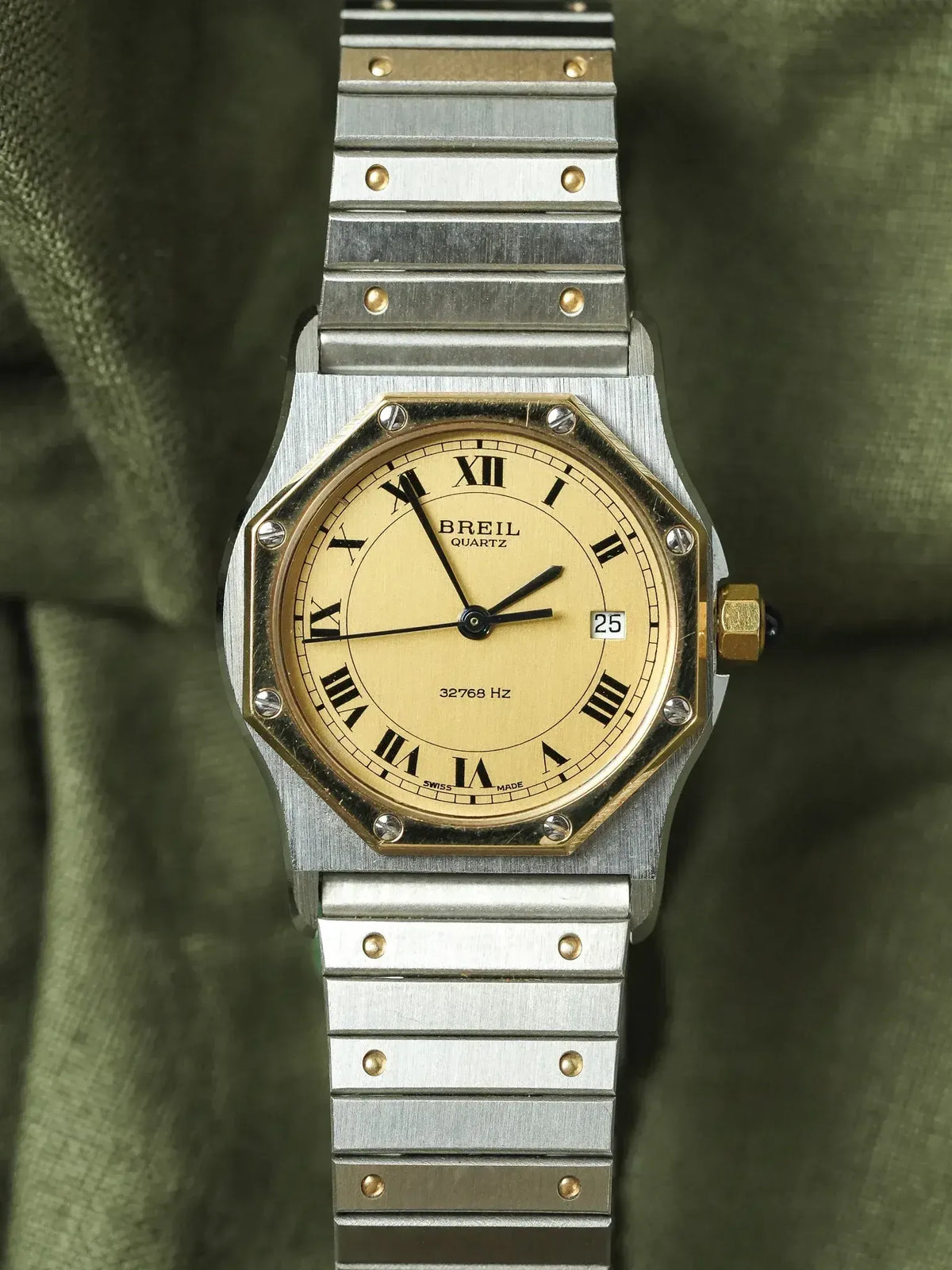Breil Quartz vintage watch with gold dial, Roman numerals, steel bracelet on olive fabric