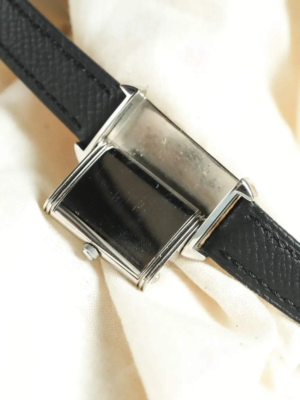 Vintage rectangular watch with black dial, silver case, and textured black leather strap
