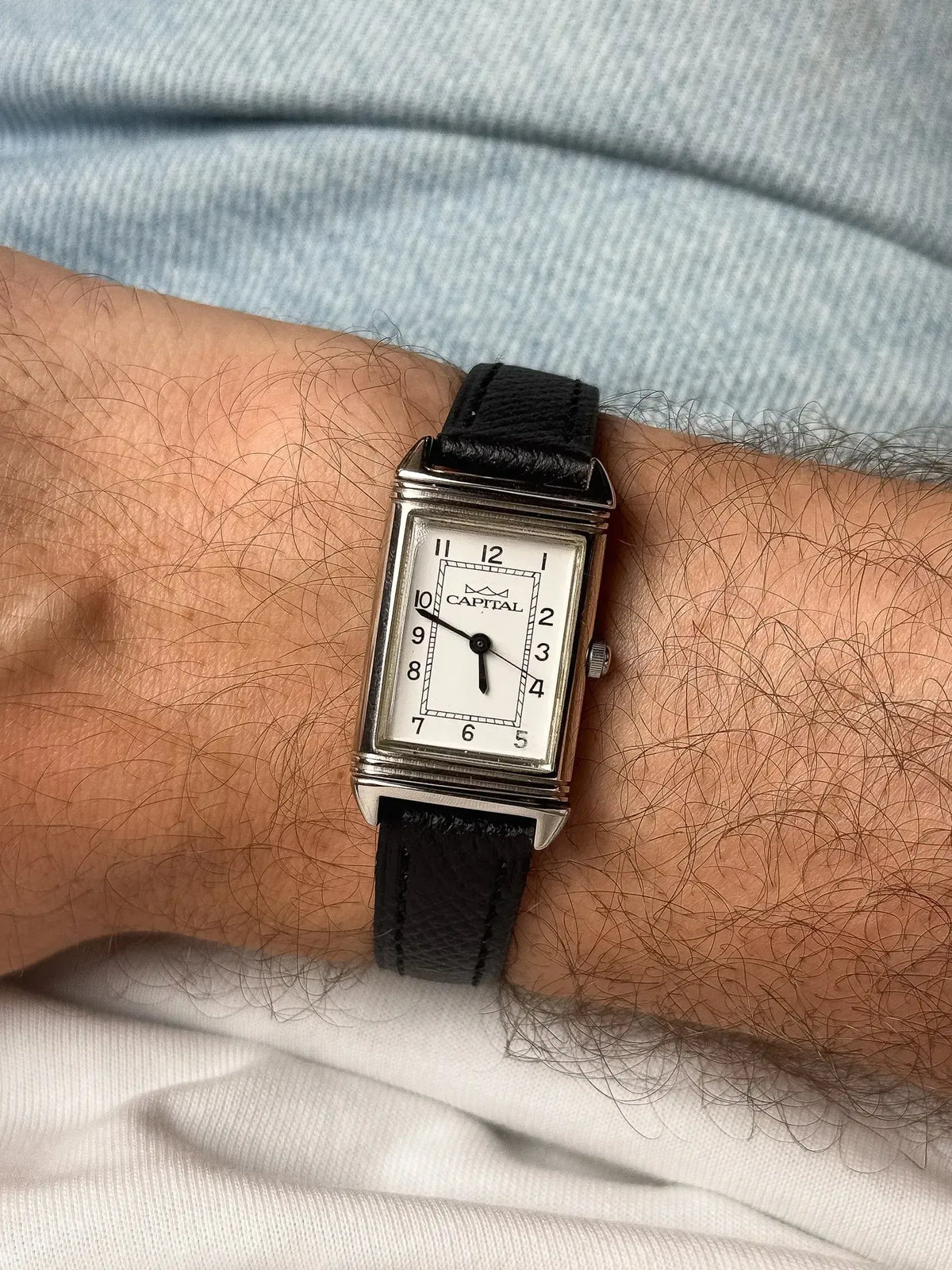 Capital vintage rectangular watch with white dial, black leather strap, worn on wrist