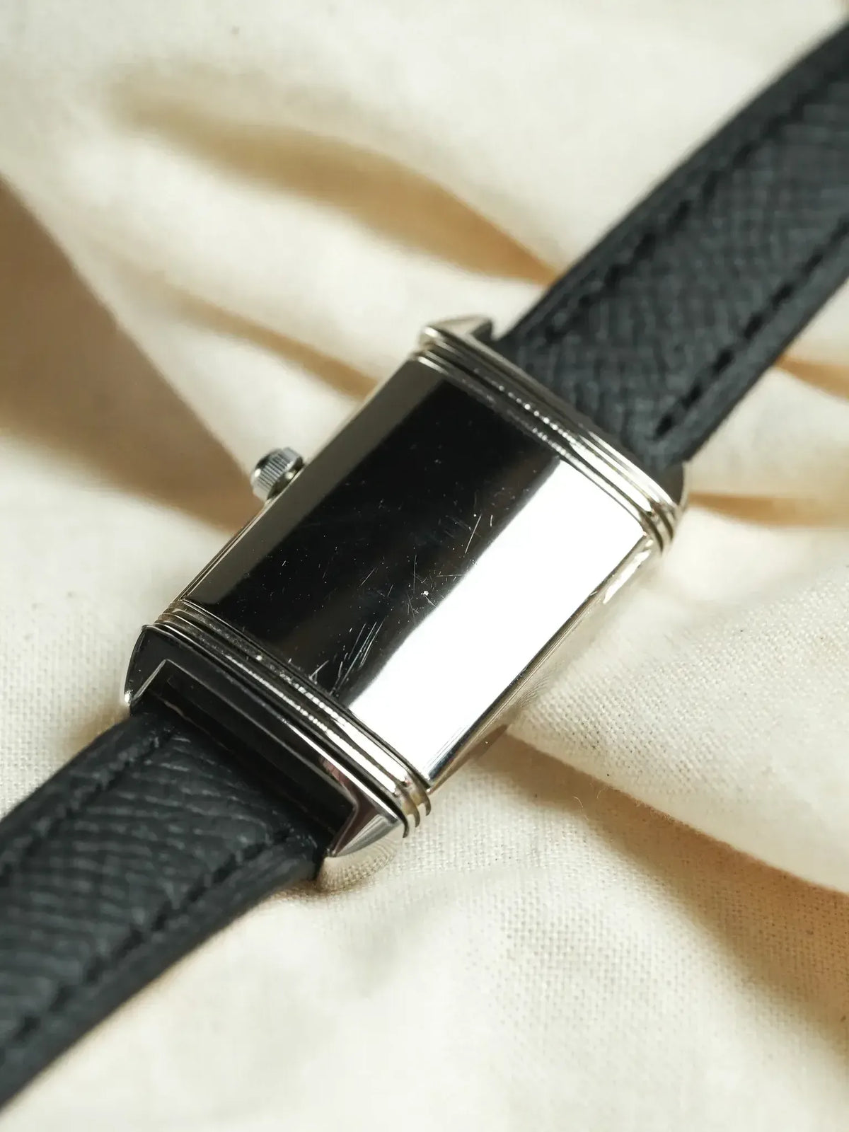Vintage Cartier Tank watch with black dial, steel case, and textured leather strap