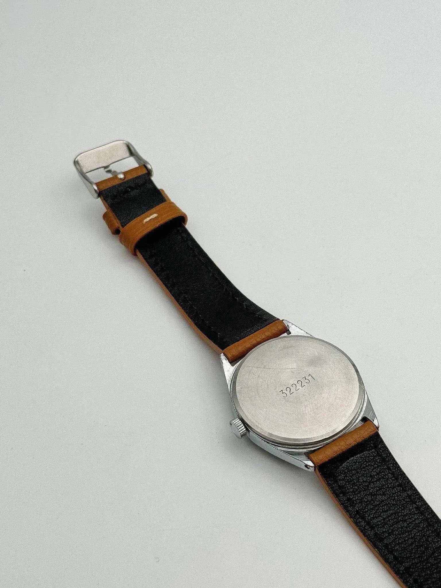 Vintage watch with stainless steel case, black leather strap, and engraved case back