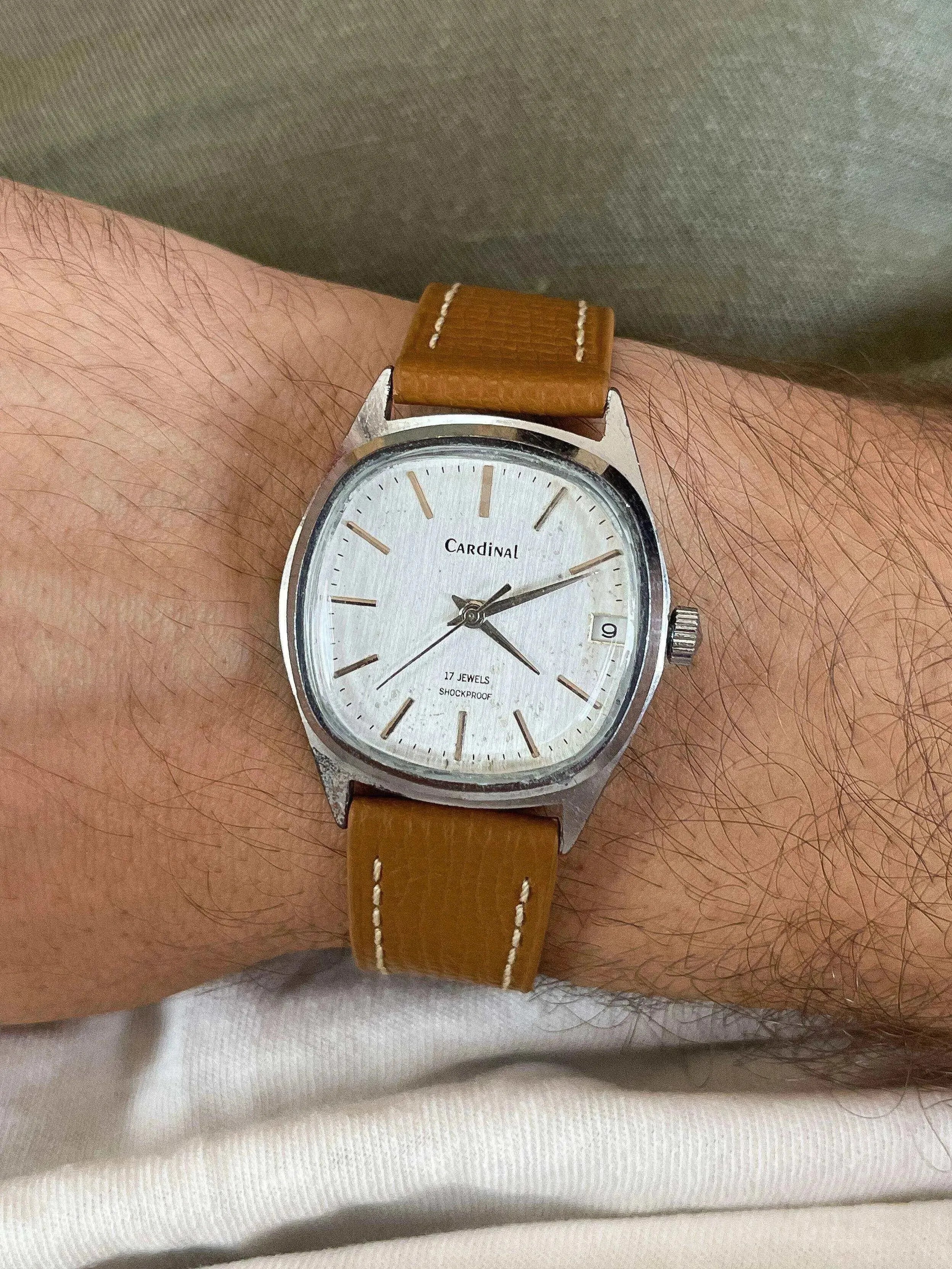 Cardinal vintage watch with silver dial, brown leather strap, worn on wrist