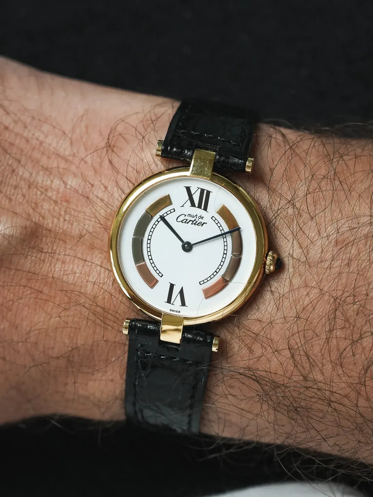 Cartier Must de Cartier vintage watch with gold case, white dial, black leather strap on wrist