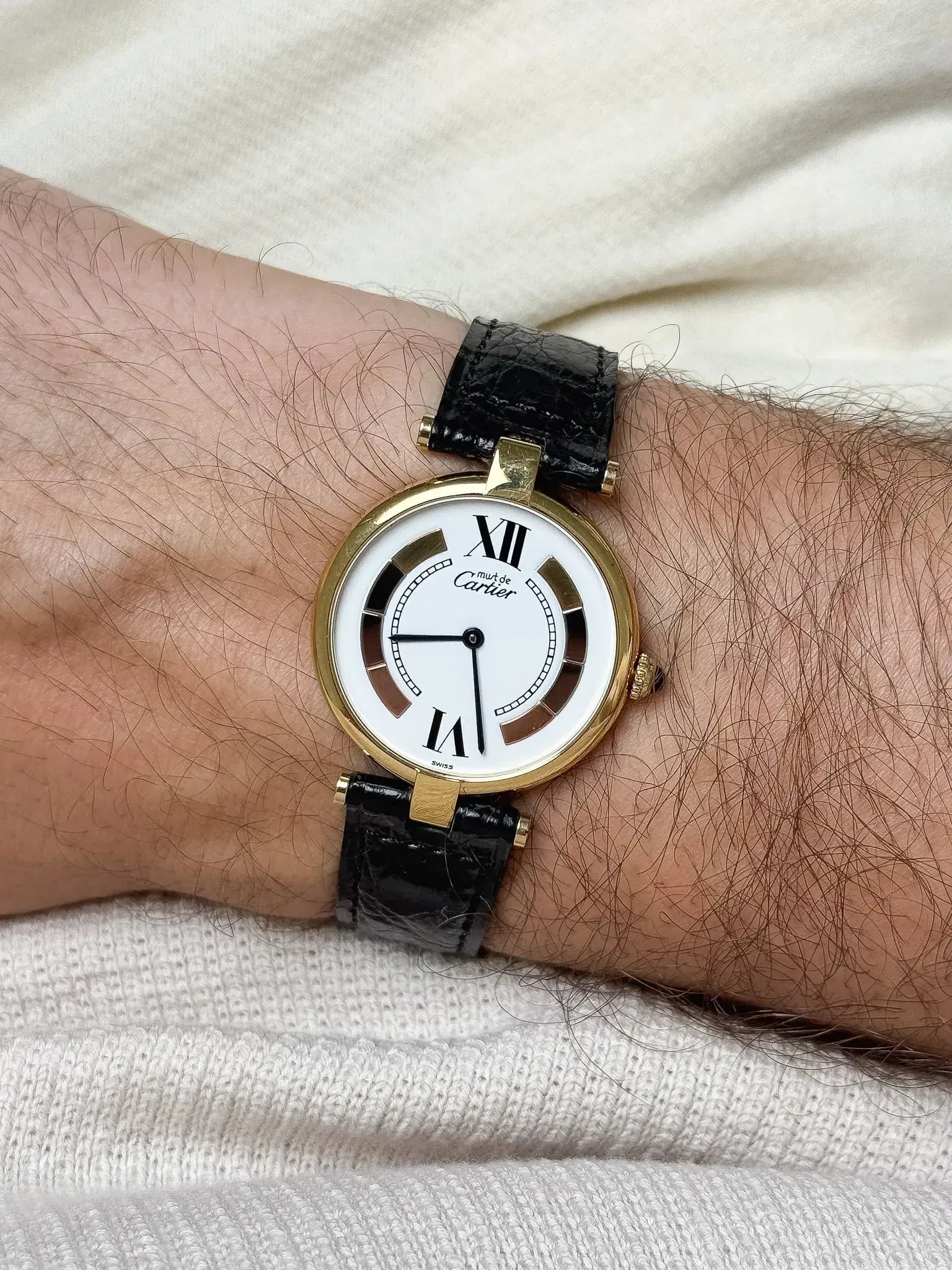 Cartier Must de Cartier vintage watch with gold case, white dial, black leather strap on wrist