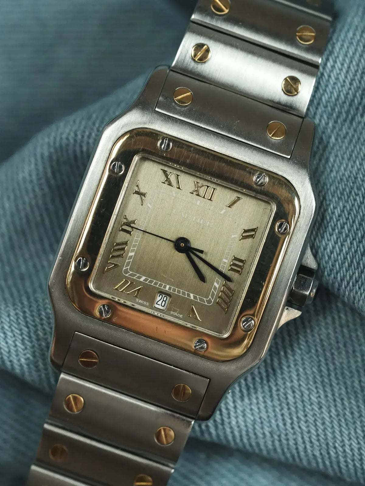 Cartier Santos vintage watch with gold-toned dial, steel case, and bracelet on denim