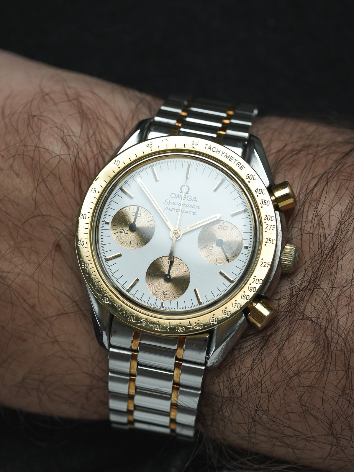 Omega Speedmaster vintage chronograph with white dial, gold accents, worn on wrist