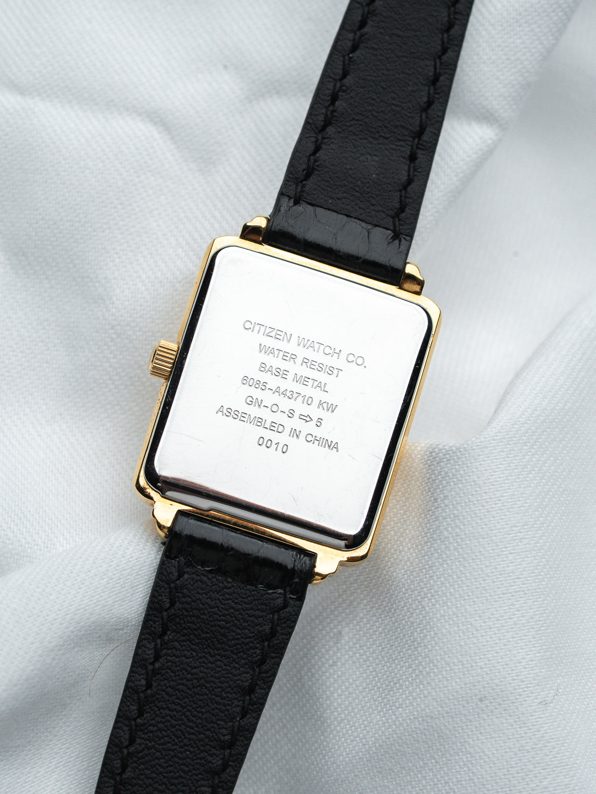 Citizen watch with gold case, black leather strap, and engraved back details