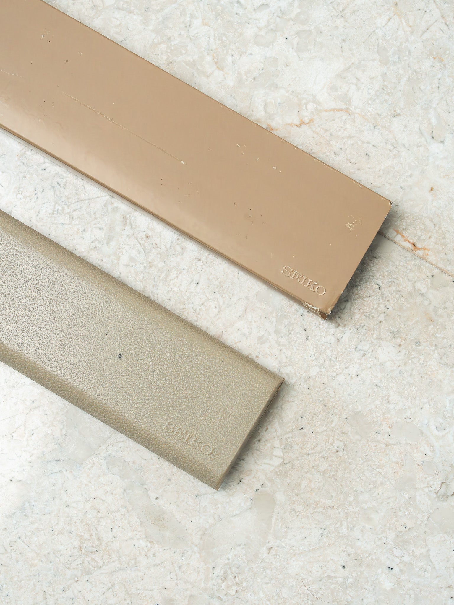 Seiko vintage watch boxes in beige, one smooth and one textured, on marble surface