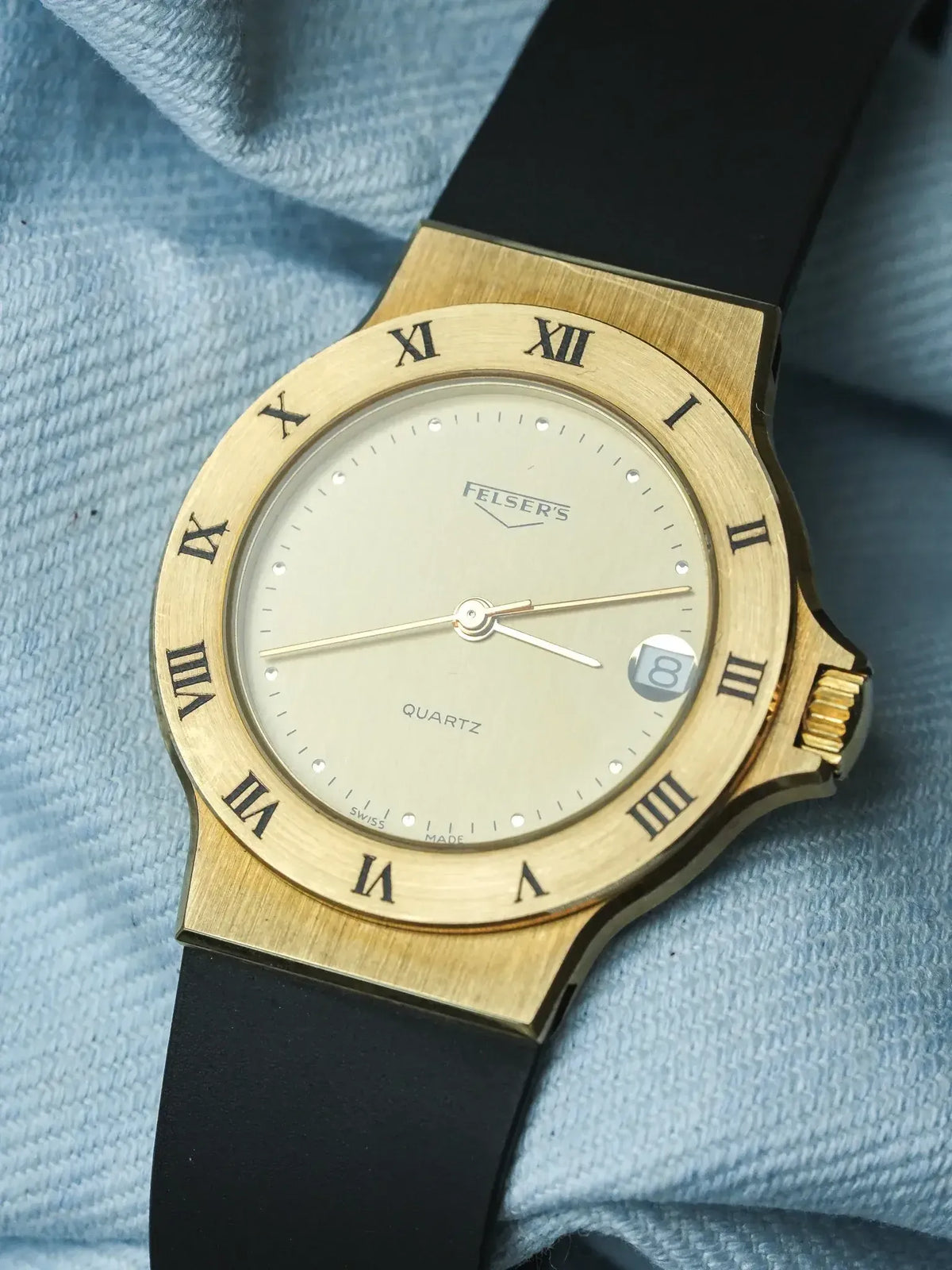 Felser's vintage watch with gold case, Roman numerals, and black strap