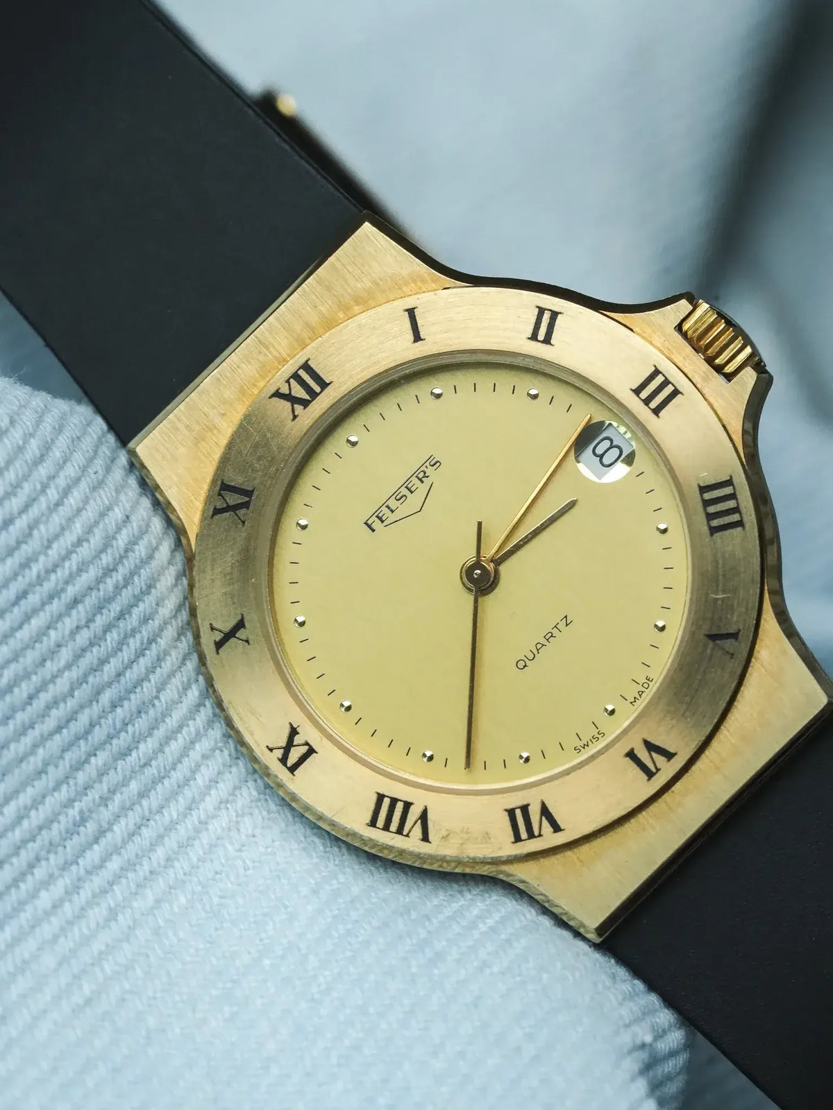 Felser's vintage quartz watch with gold case, cream dial, Roman numerals, black strap