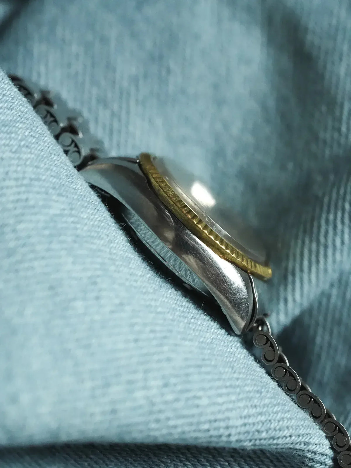 Vintage Rolex two-tone watch with fluted bezel resting on denim fabric