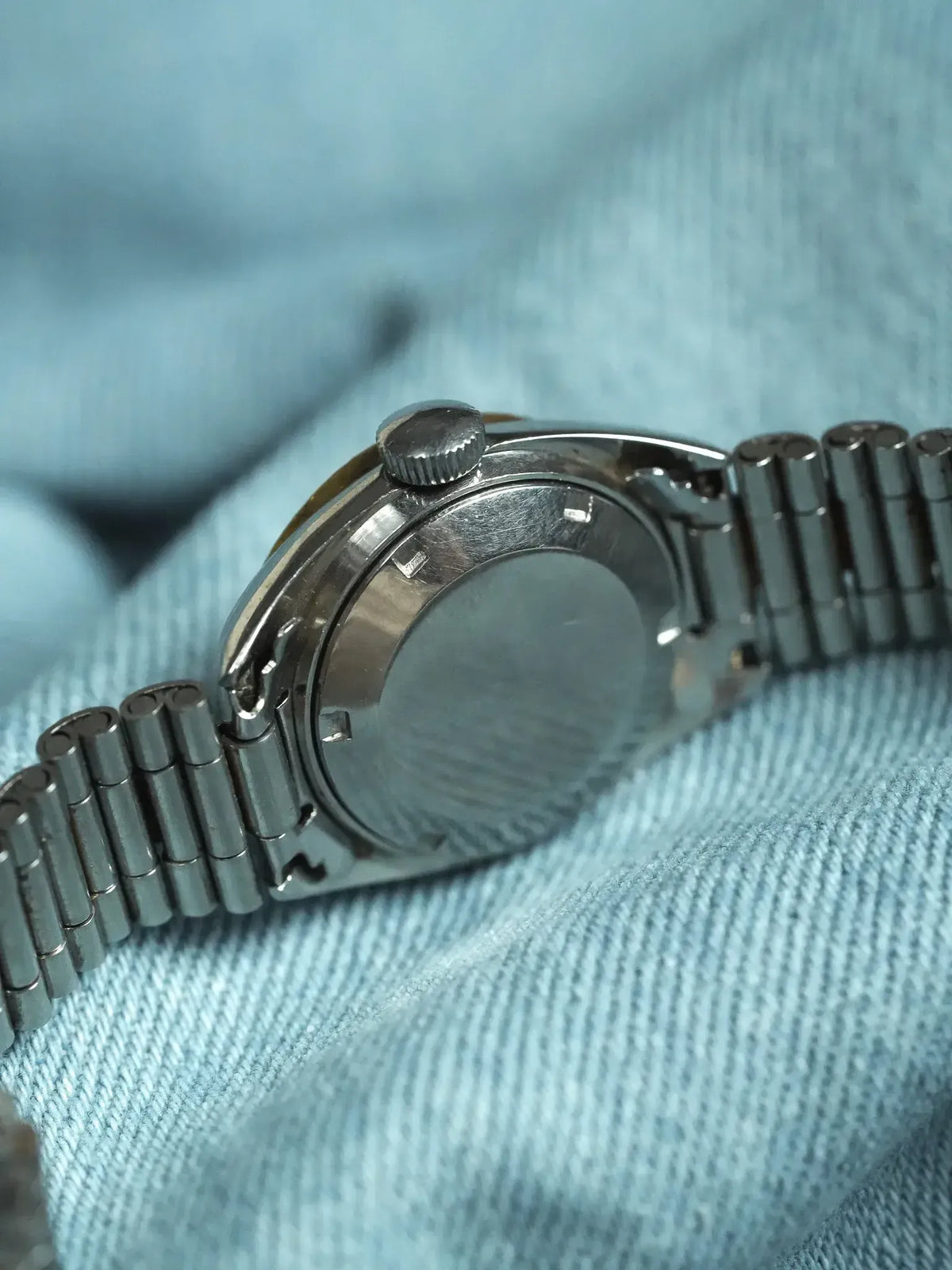 Vintage Omega watch with stainless steel case and bracelet, back view on blue fabric