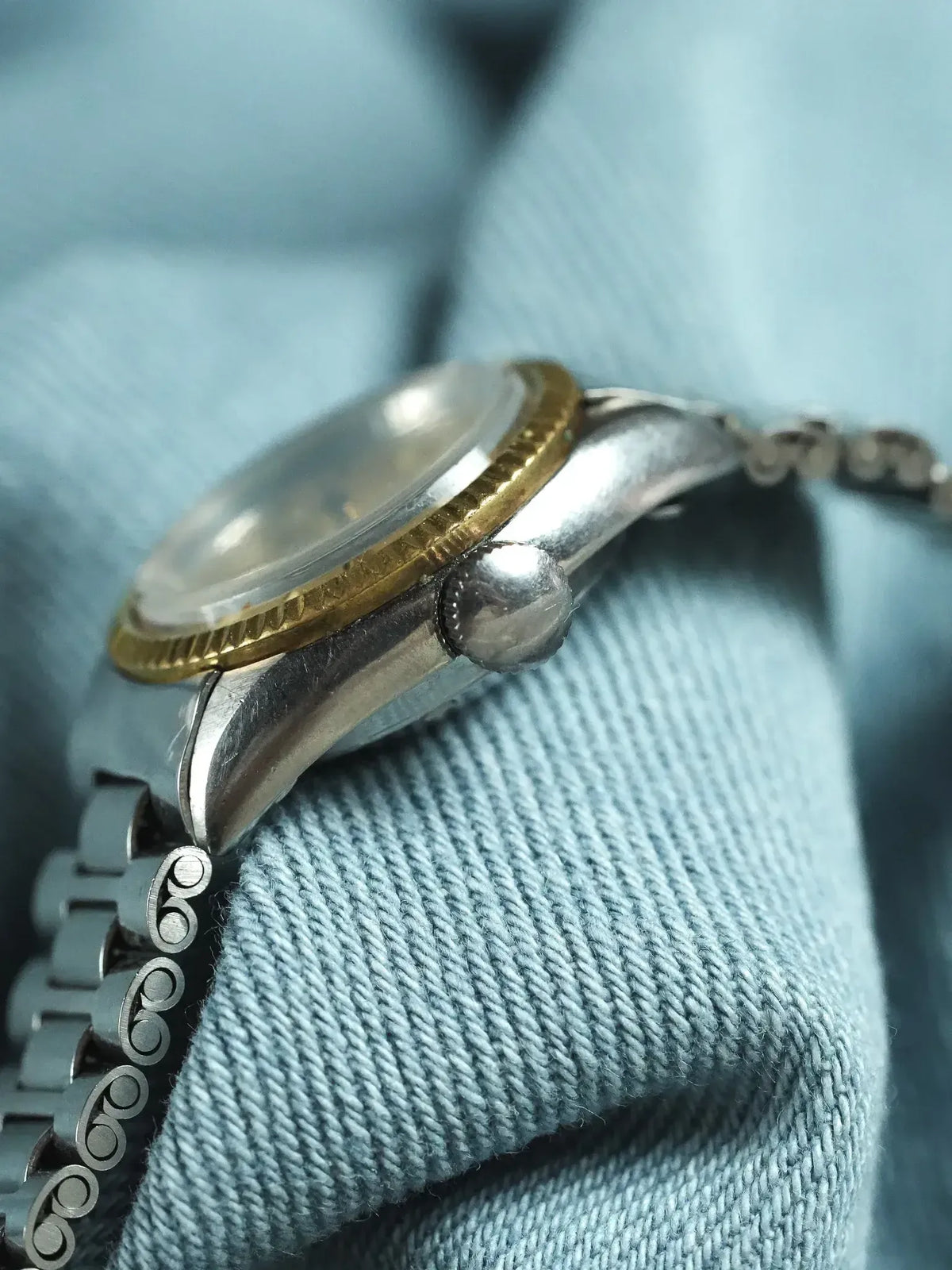 Vintage Rolex watch with gold bezel and steel case on denim background