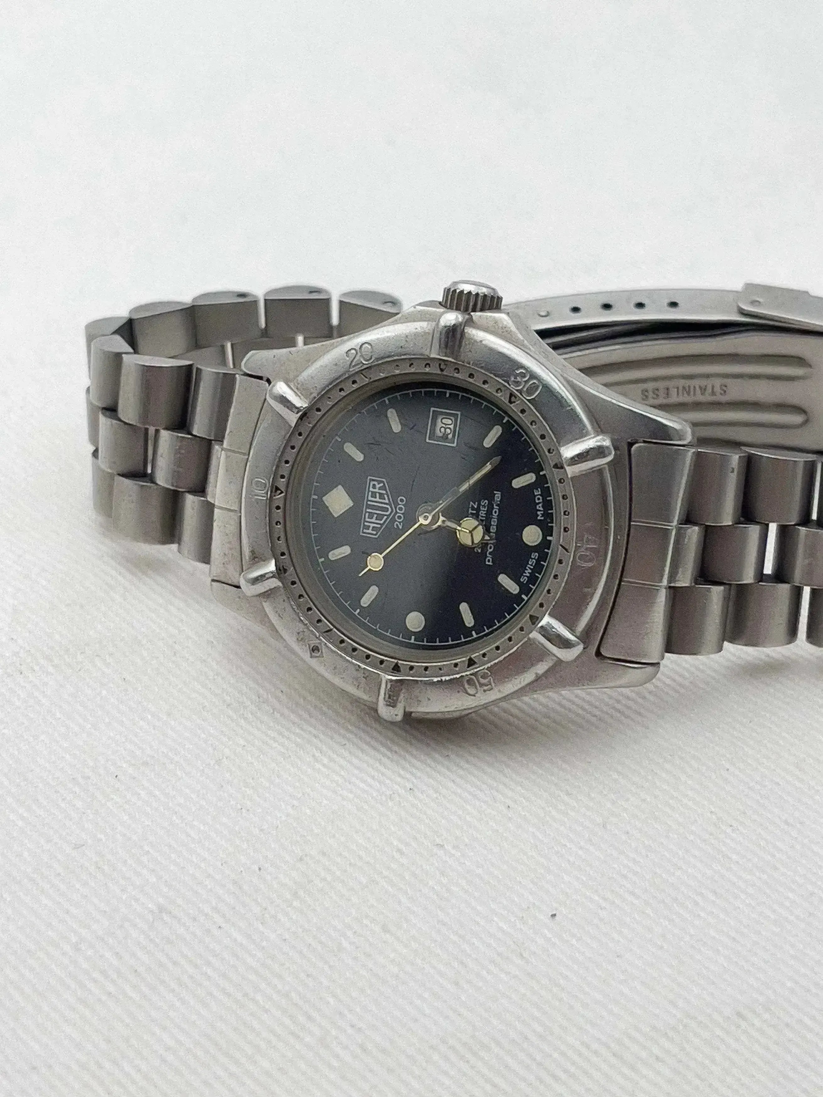Heuer 2000 vintage watch with black dial, stainless steel bracelet, on white background