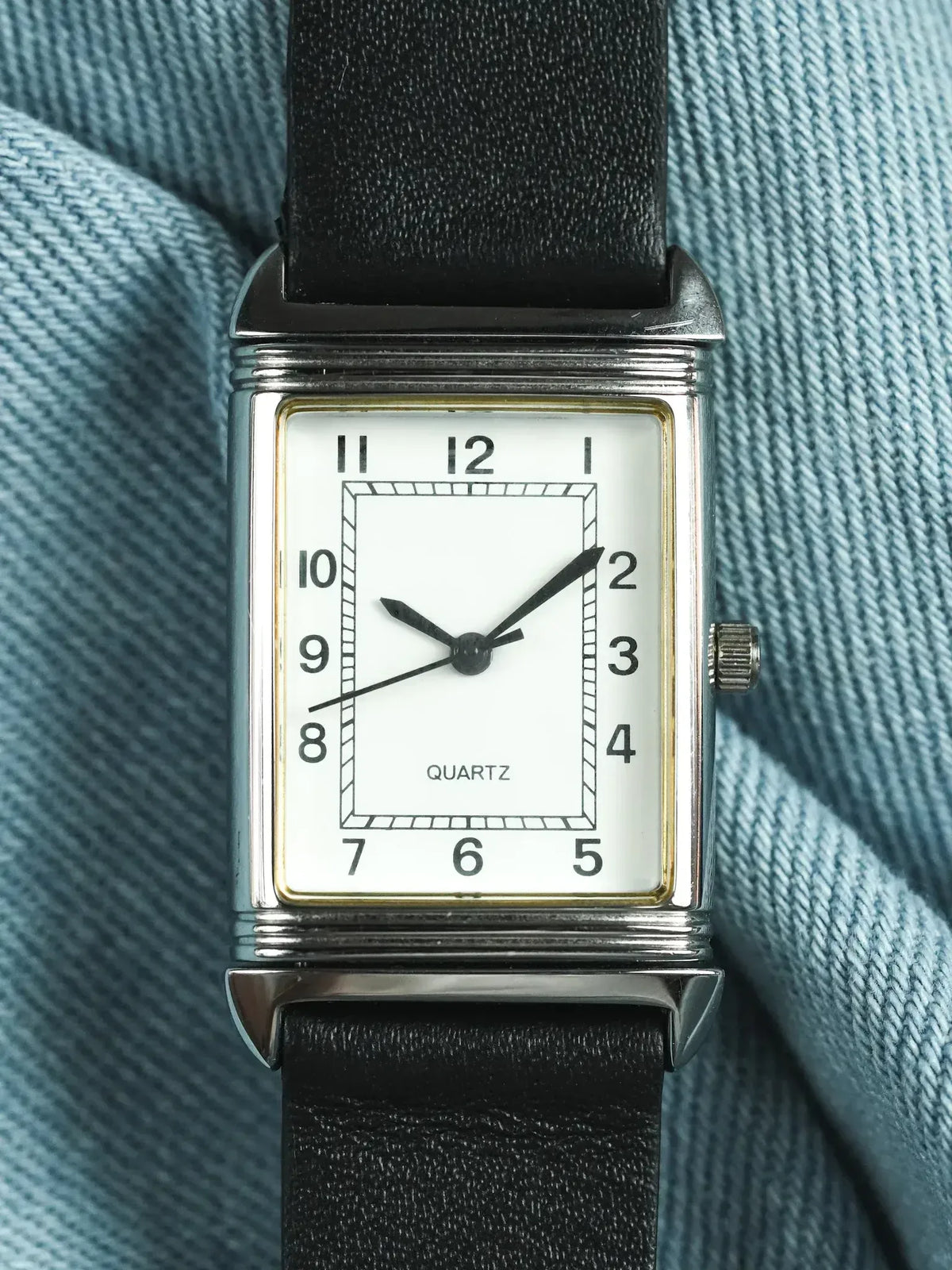 Vintage quartz watch with rectangular silver case, white dial, black leather strap