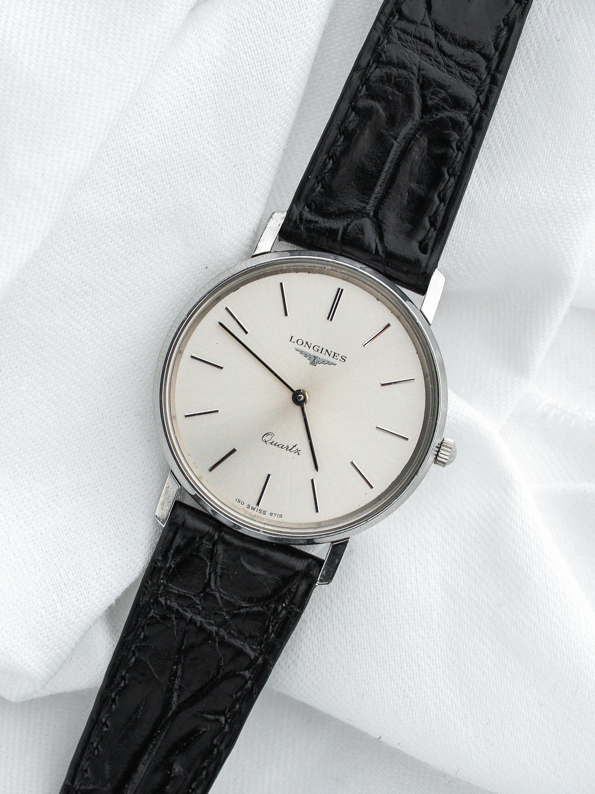 Montre Longines Quartz vintage, boîtier rond argenté, cadran blanc et bracelet cuir noir