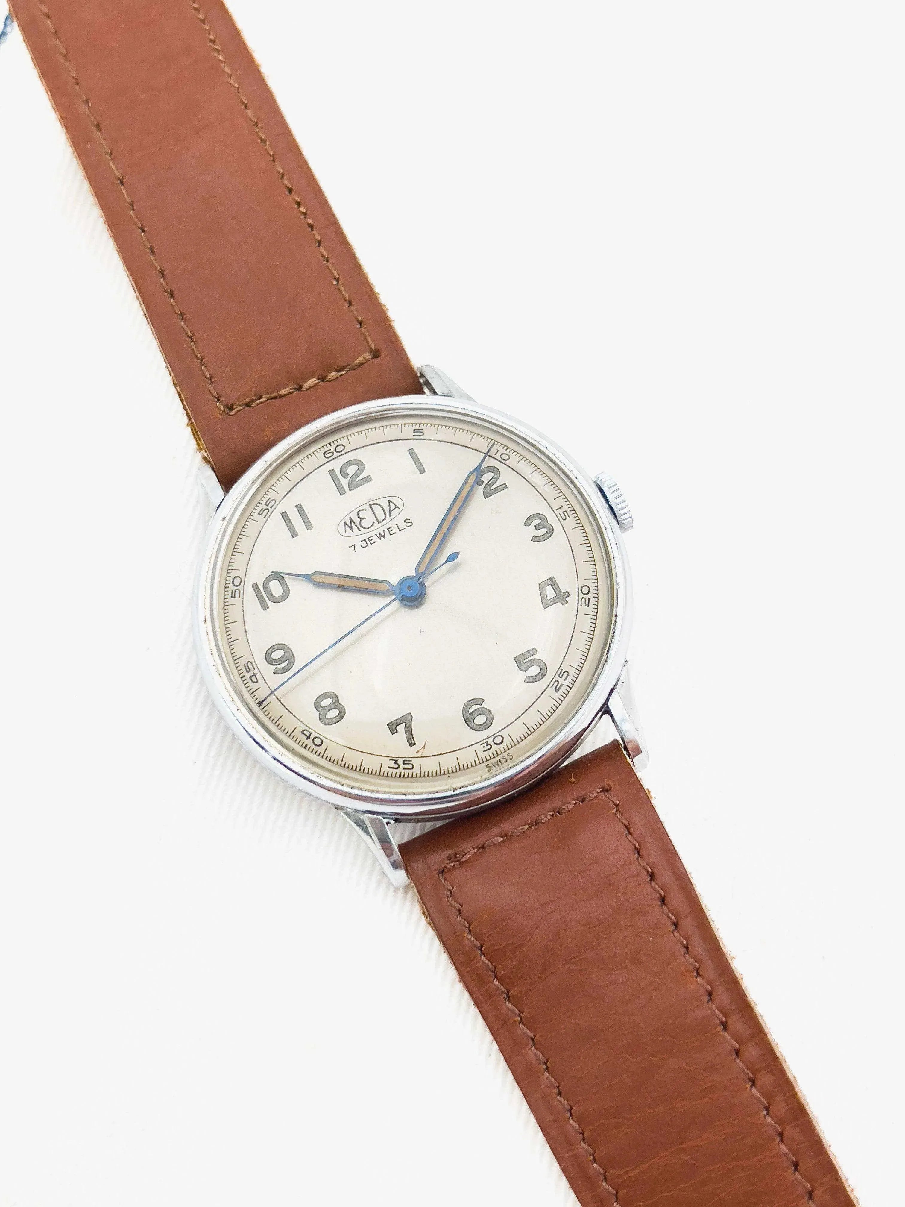 Meda vintage watch with cream dial, blue hands, and brown leather strap