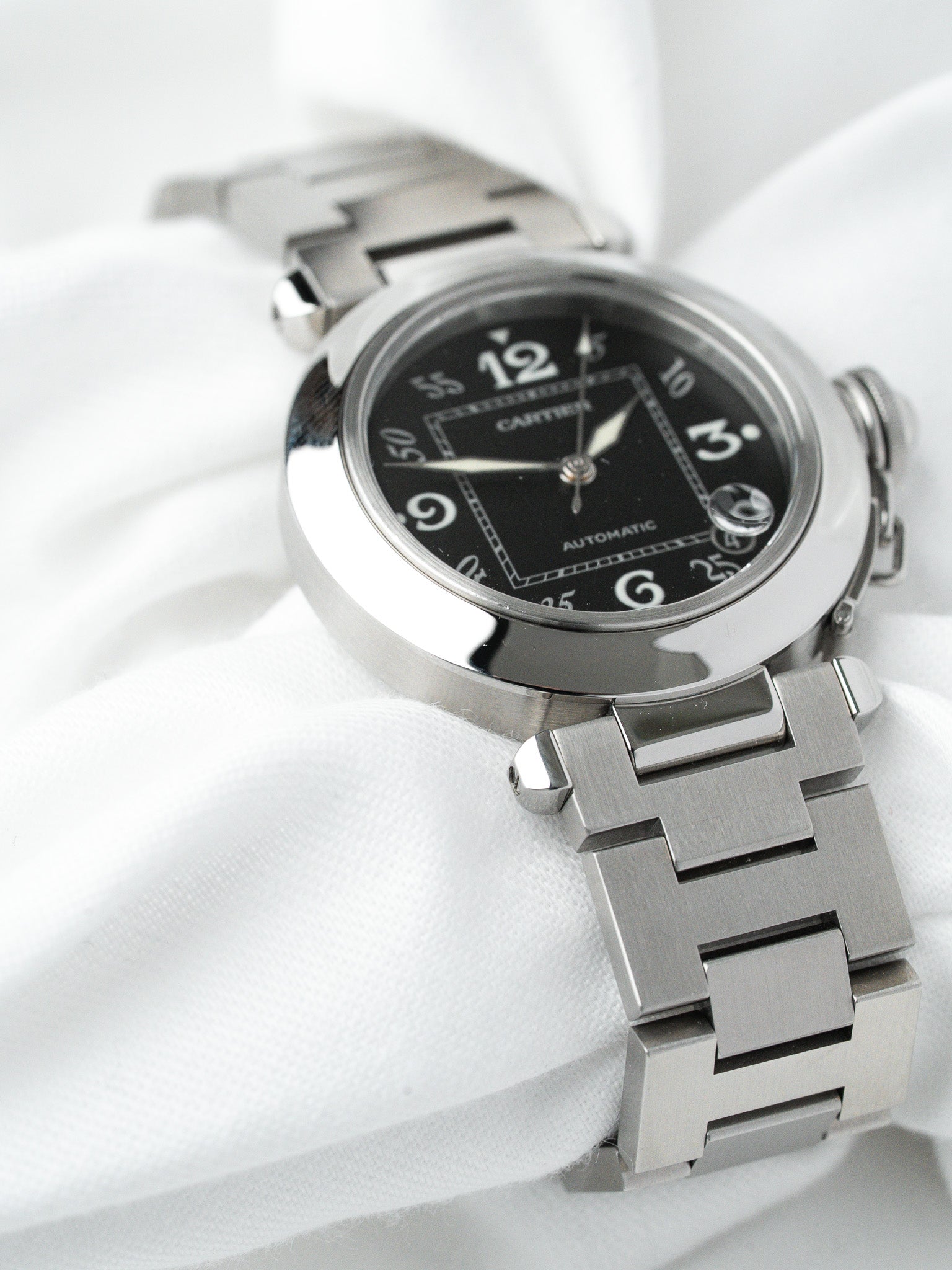 Cartier Pasha automatic watch with black dial and steel bracelet on white fabric