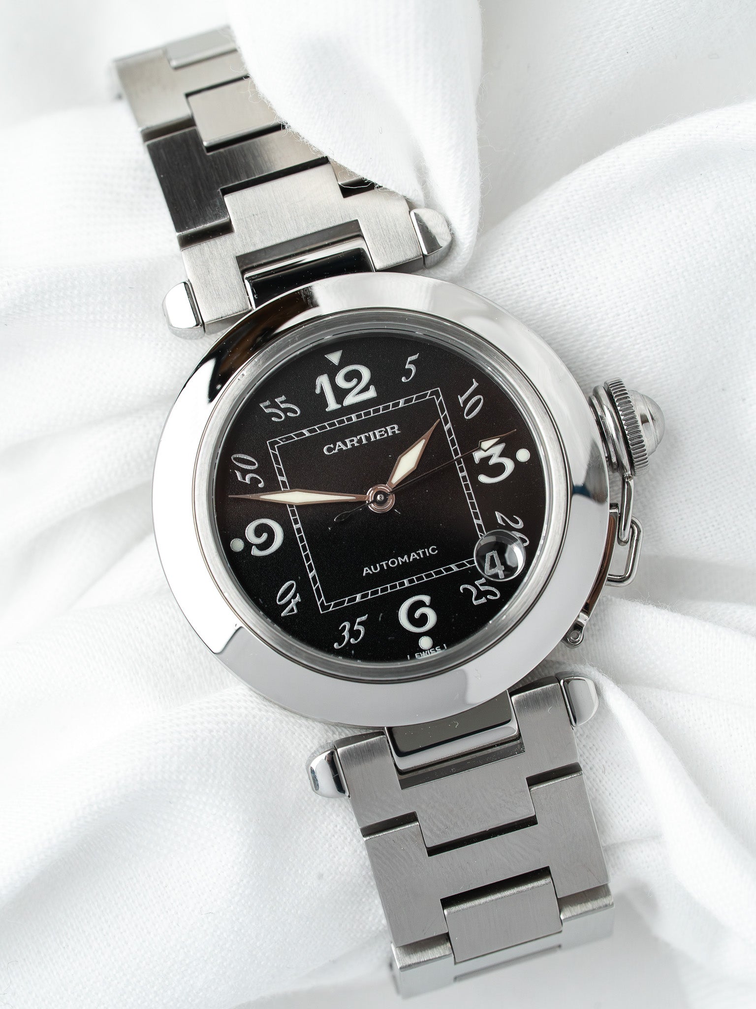 Cartier Pasha automatic watch with black dial, steel bracelet, on white fabric