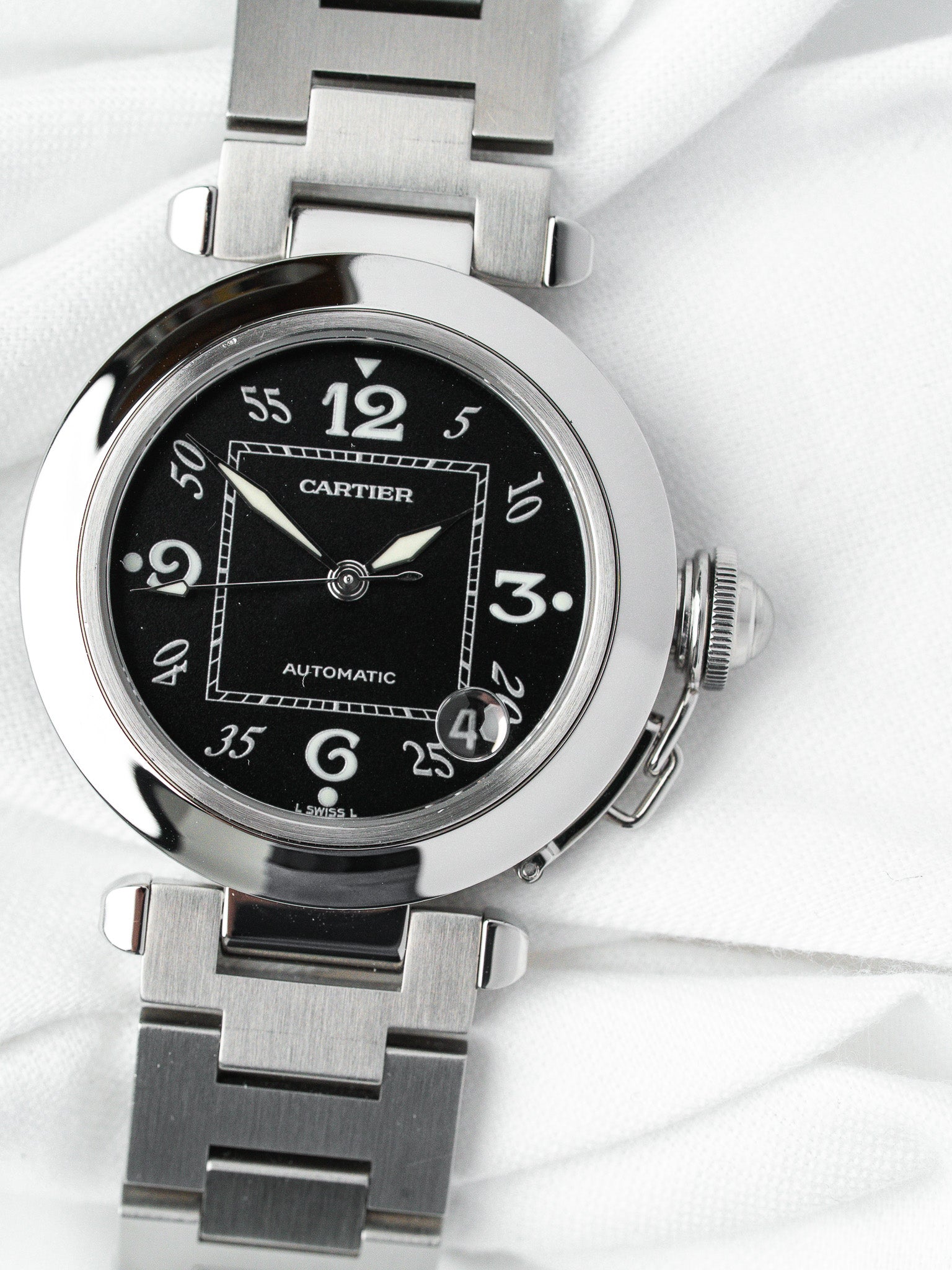 Cartier Pasha automatic watch with black dial, steel case and bracelet on white fabric