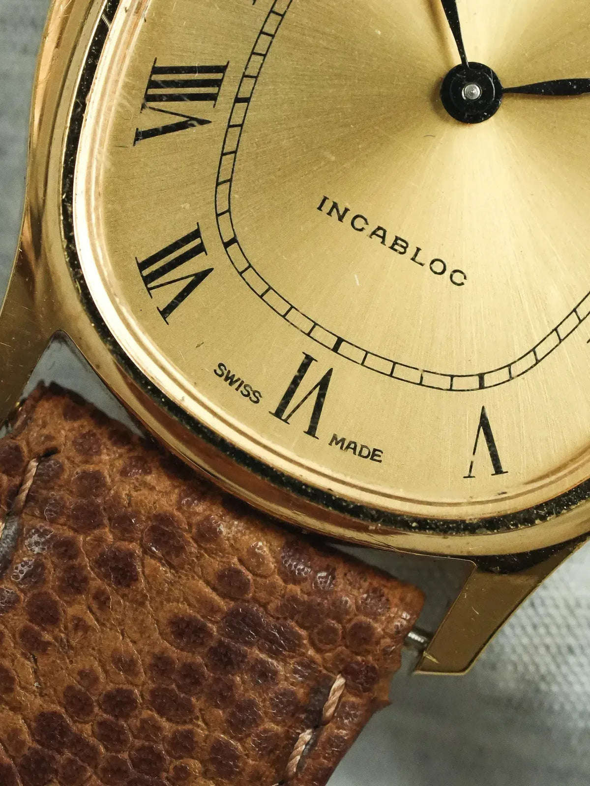 Incabloc vintage watch with gold dial, Roman numerals, and brown textured leather strap