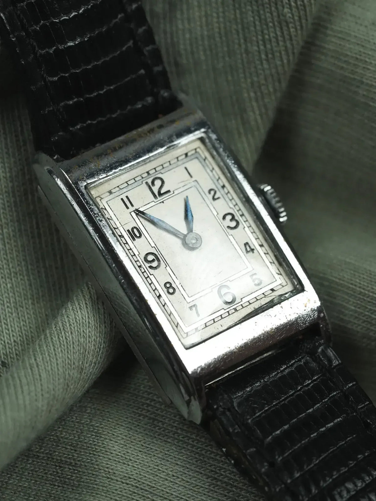 Vintage rectangular watch with silver case, white dial, black leather strap