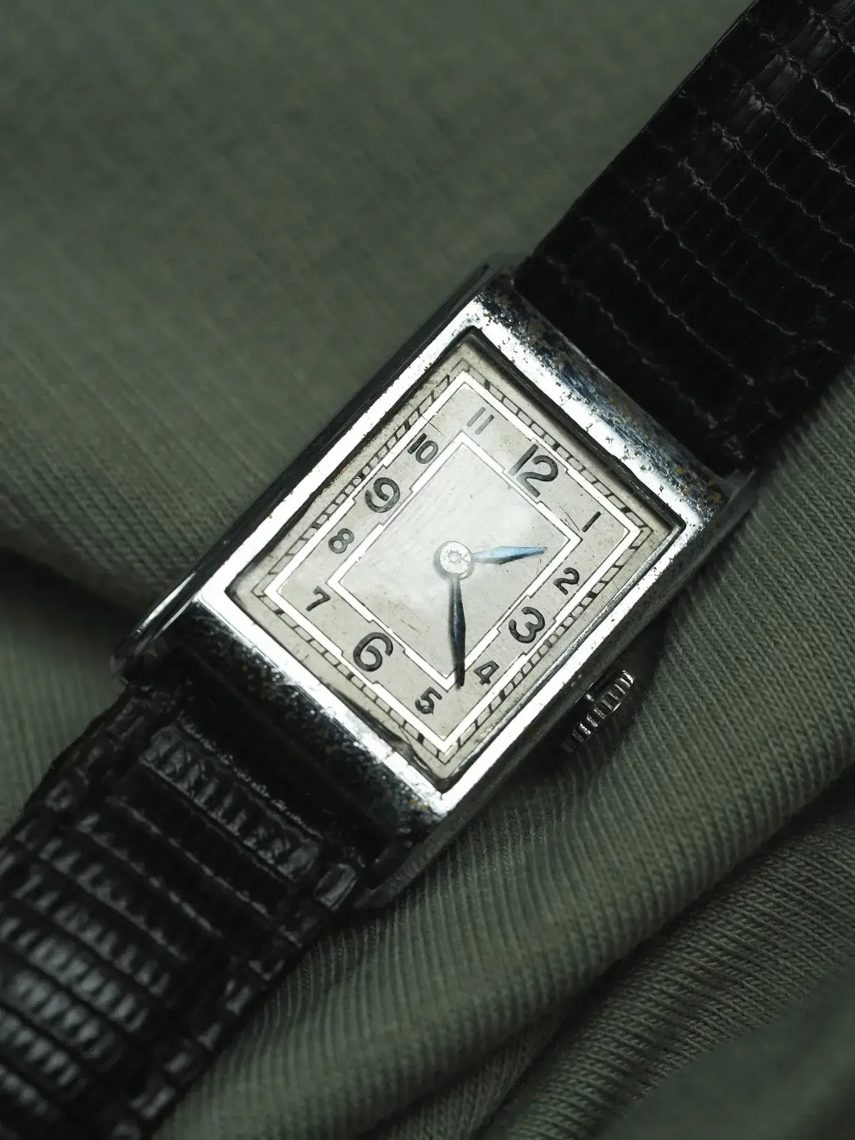 Vintage rectangular watch with silver dial, black alligator strap, Art Deco numerals on green fabric