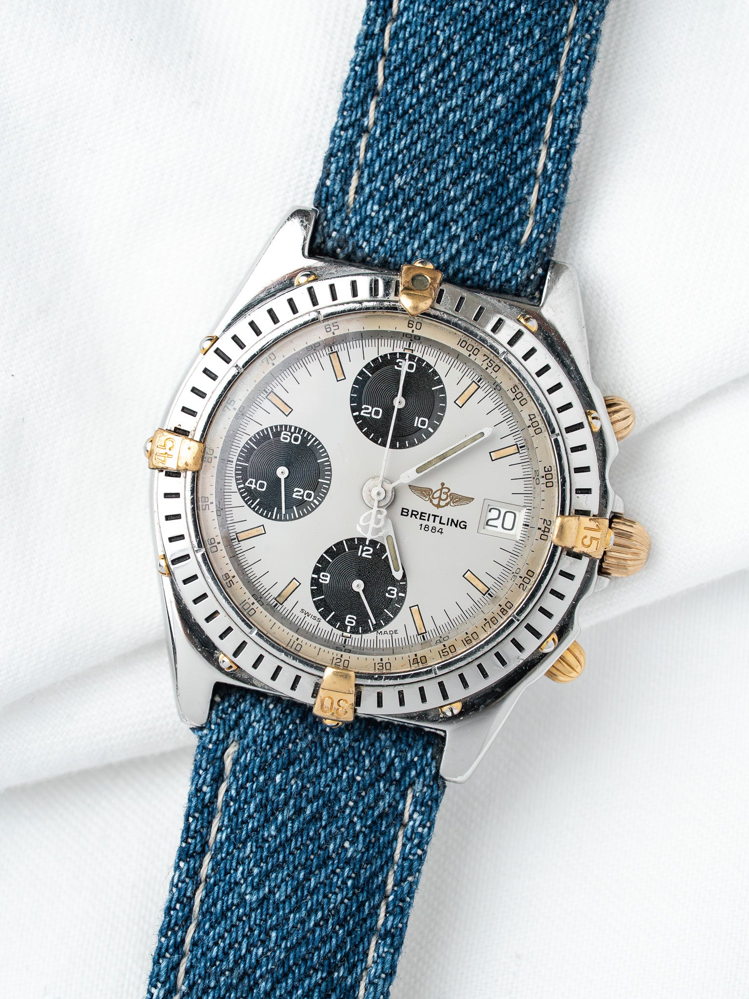 Breitling chronograph watch with silver dial, black subdials, and blue denim strap