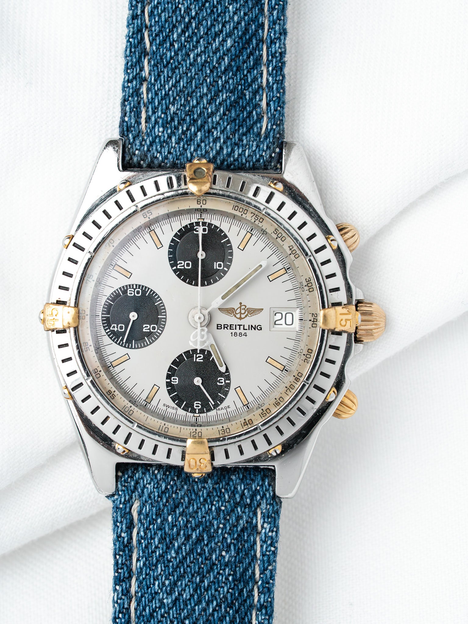 Breitling chronograph watch with silver dial, black subdials, and blue denim strap