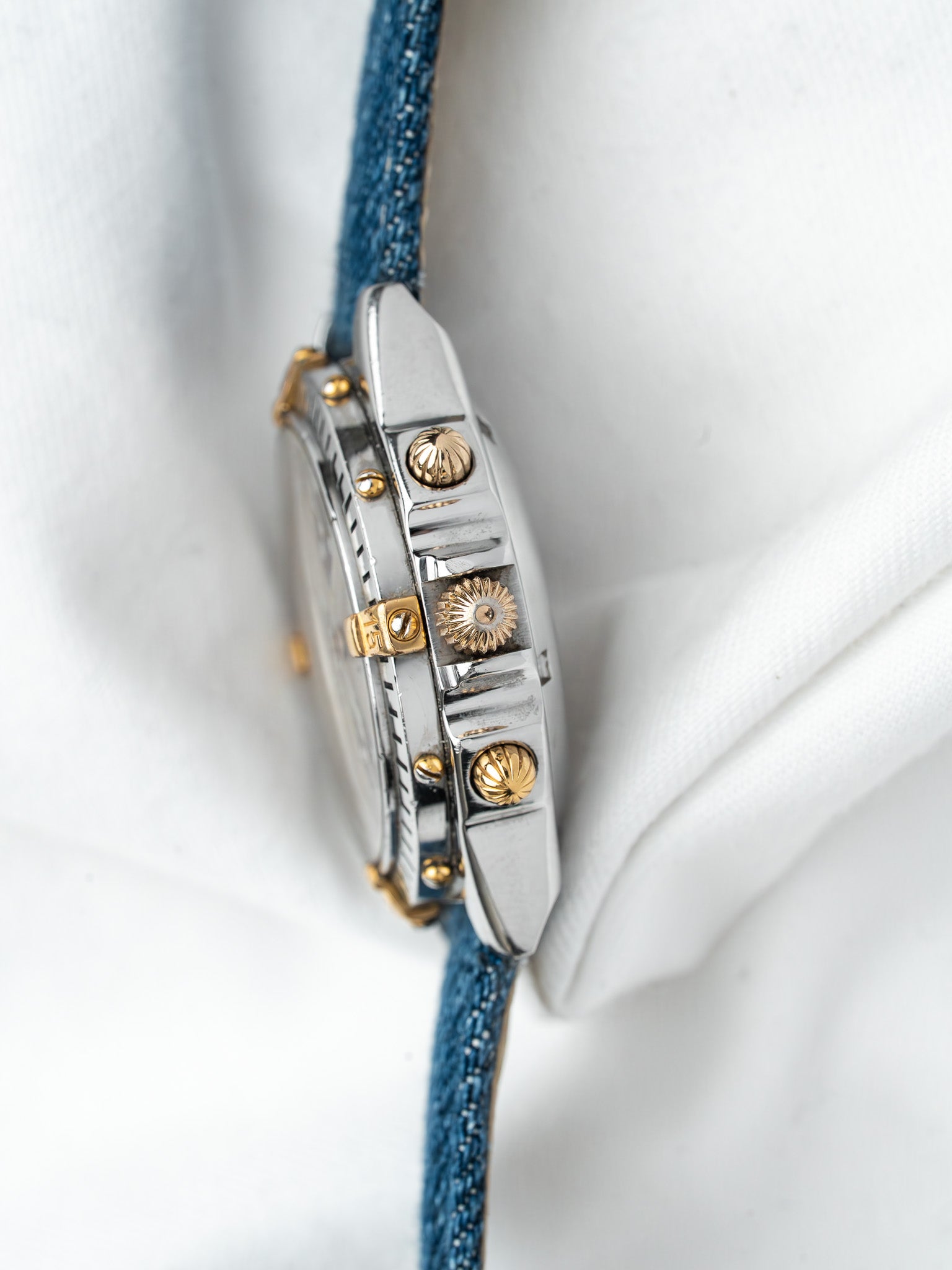 Cartier vintage watch with gold accents and blue fabric strap on white background