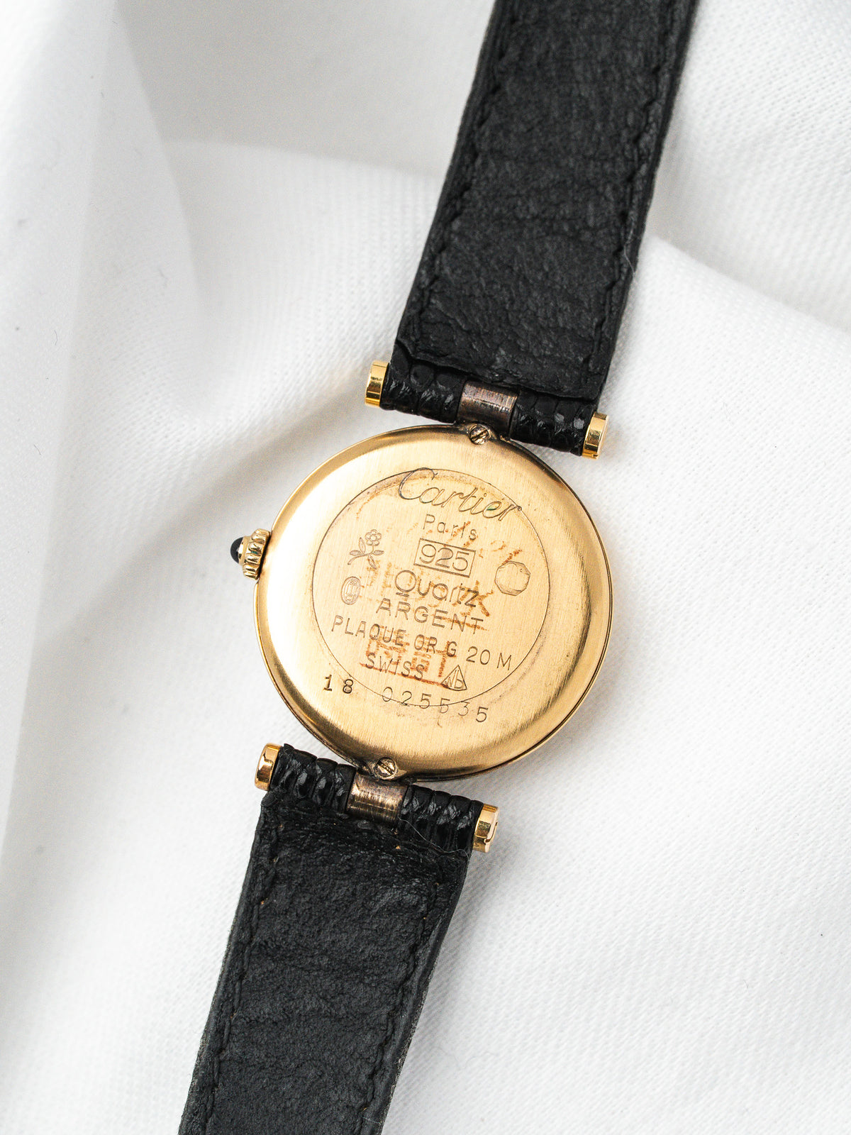 Cartier vintage watch with gold case, black leather strap, and engraved back details