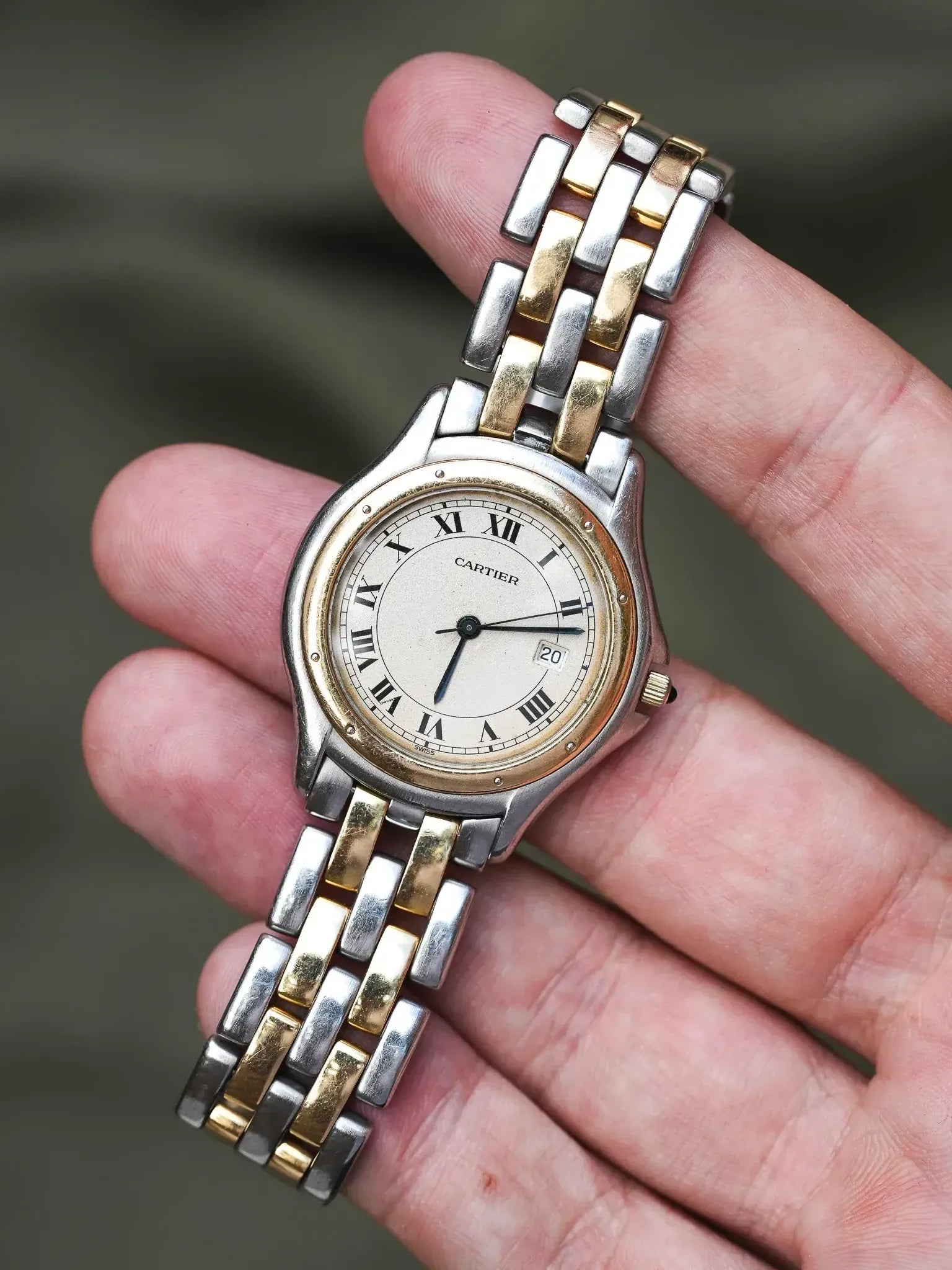 Cartier vintage watch with two-tone bracelet, cream dial, Roman numerals, held in hand