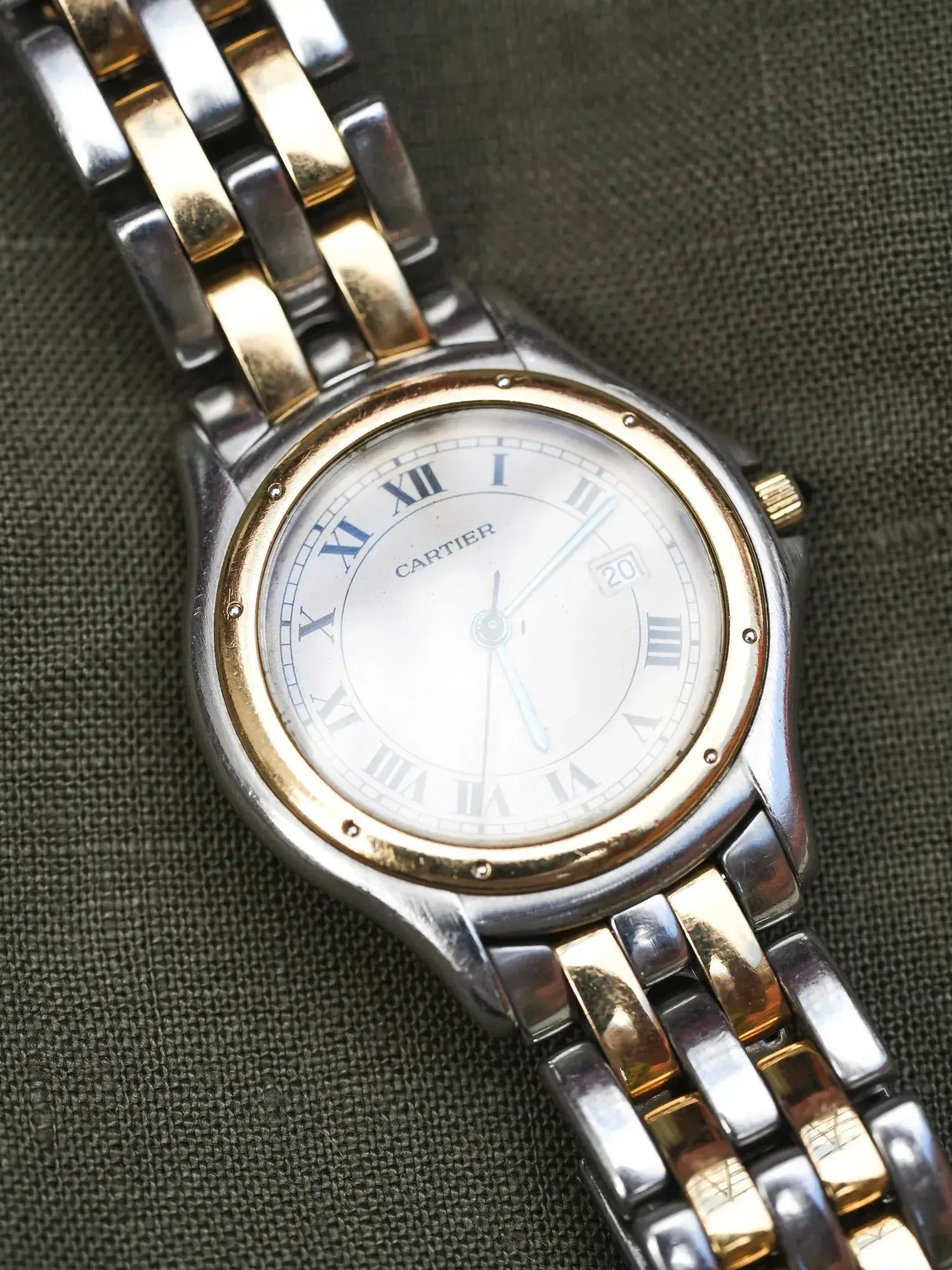 Cartier vintage watch with silver dial, Roman numerals, two-tone bracelet on textured background
