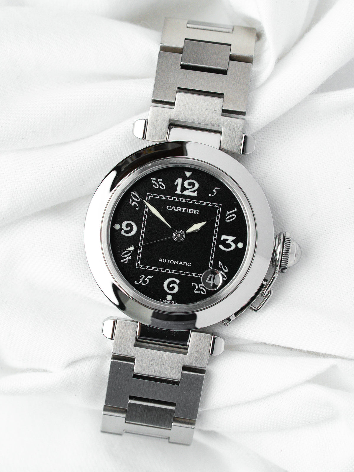 Cartier Pasha automatic watch with black dial and stainless steel bracelet on white fabric