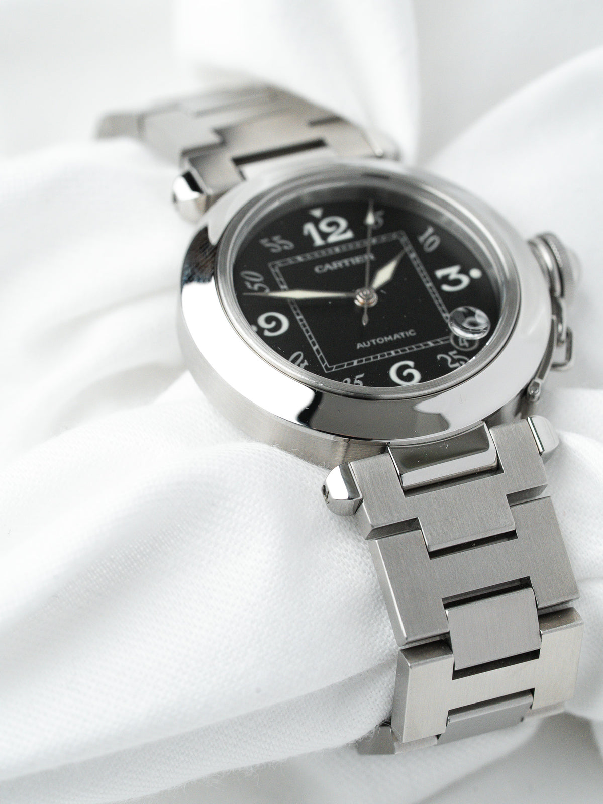 Cartier Pasha automatic watch with black dial and steel bracelet on white fabric