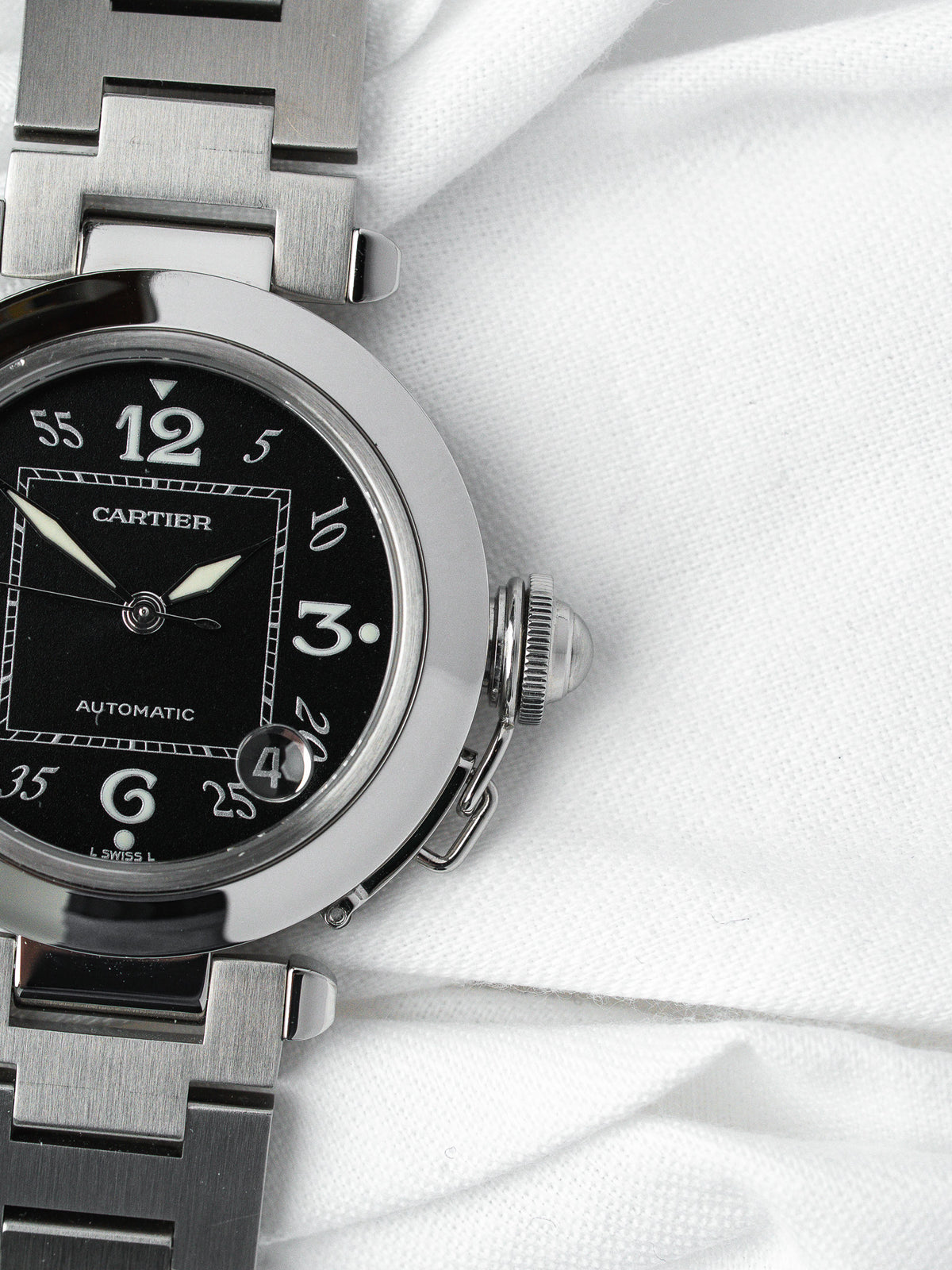 Cartier Pasha automatic watch with black dial, steel case and bracelet on white fabric