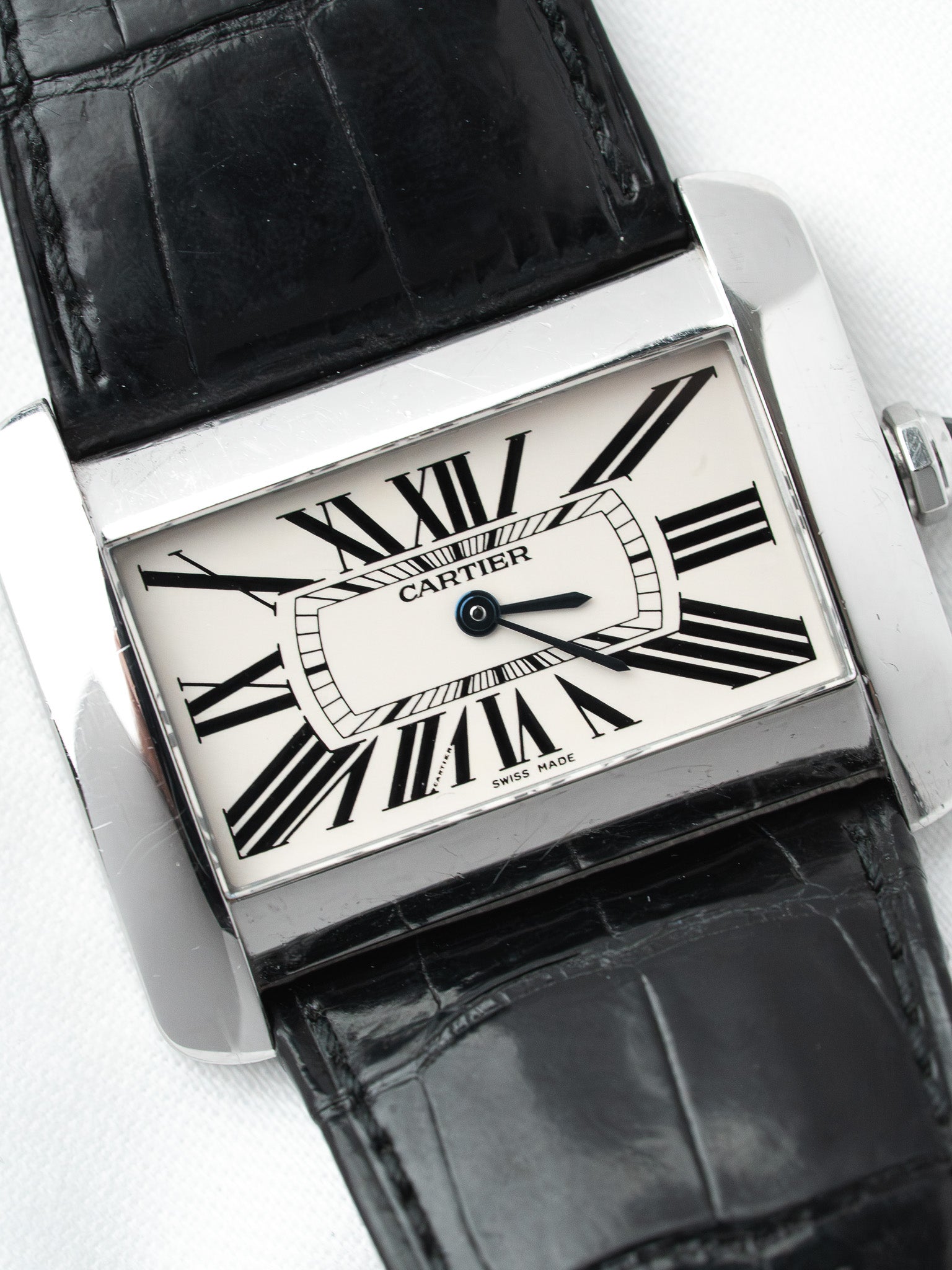 Cartier Tank watch with white dial, black Roman numerals, and black alligator strap