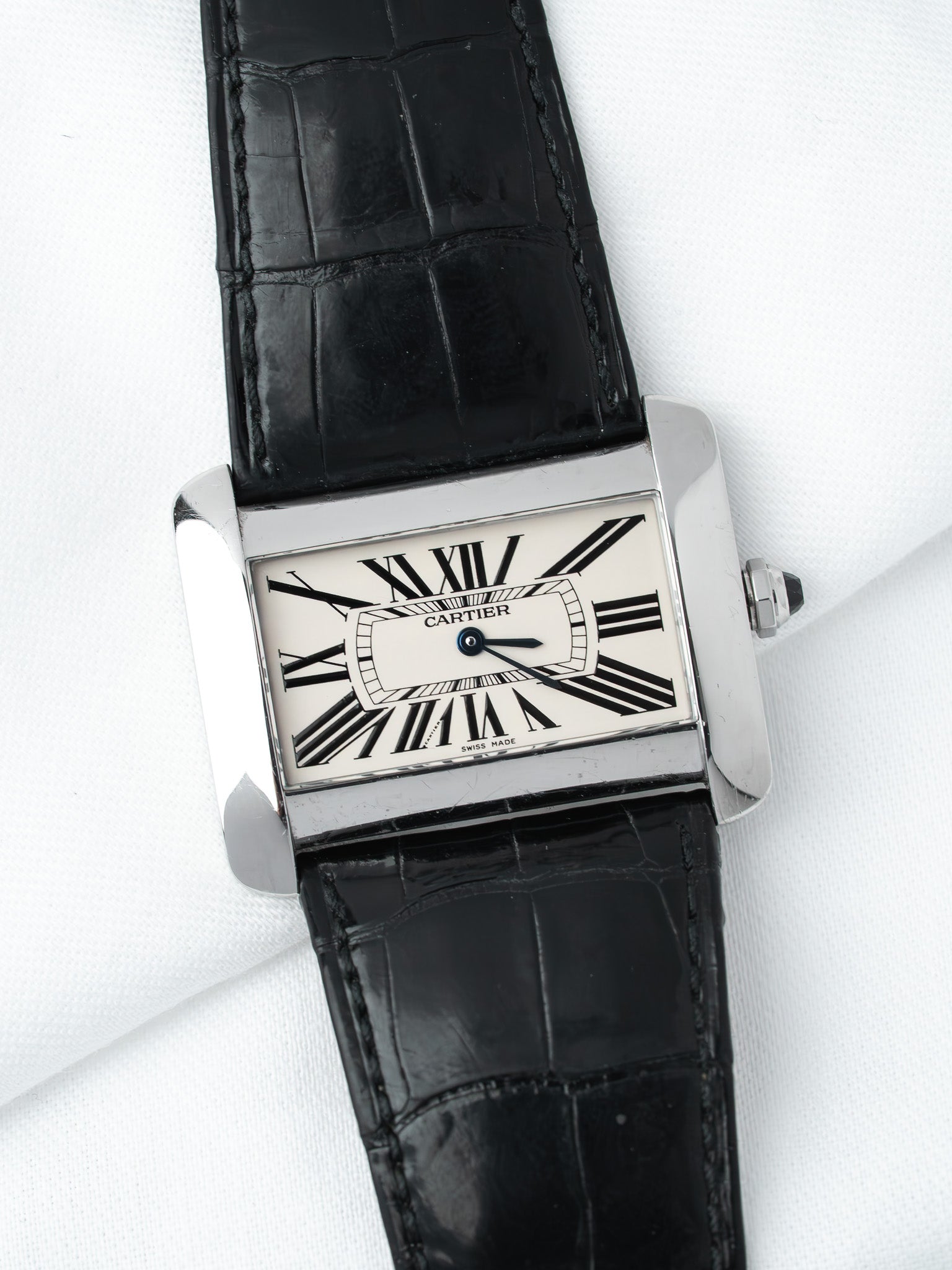 Cartier Tank watch with white dial, black Roman numerals, and black alligator strap on white background