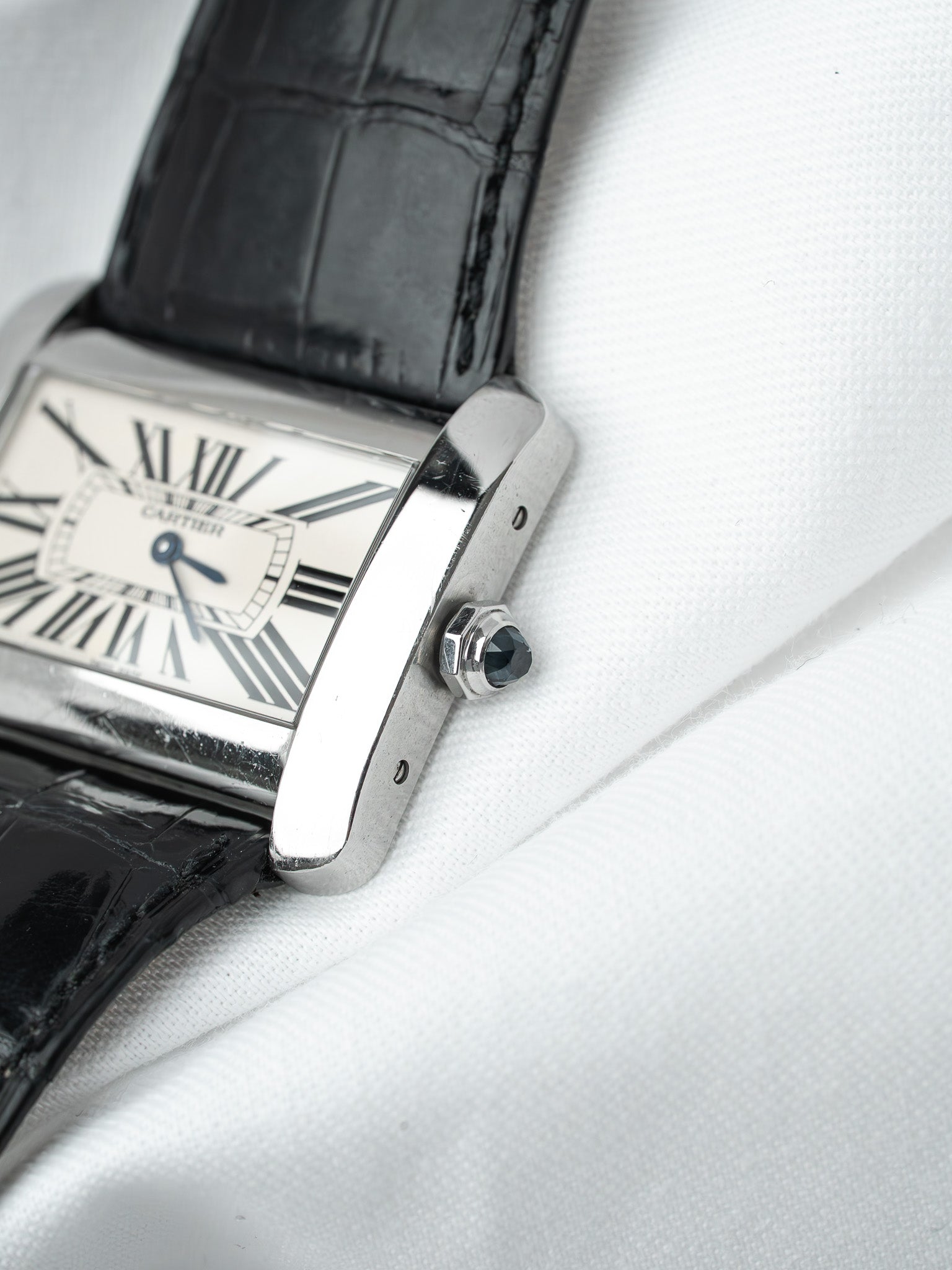 Cartier Tank watch with silver case, white dial, black alligator strap on white fabric