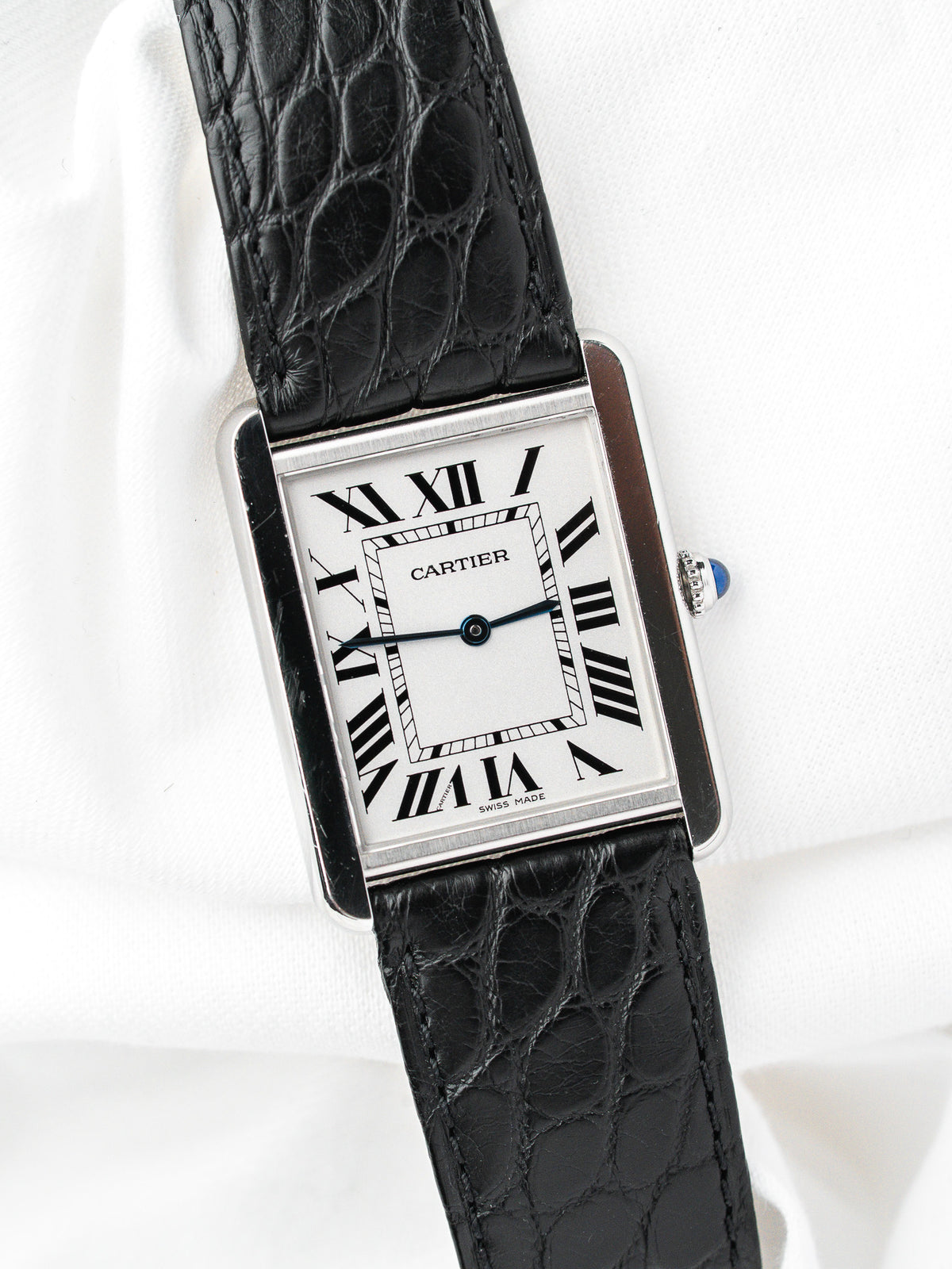 Montre Cartier Tank vintage, boîtier rectangulaire argenté, cadran blanc et bracelet cuir noir