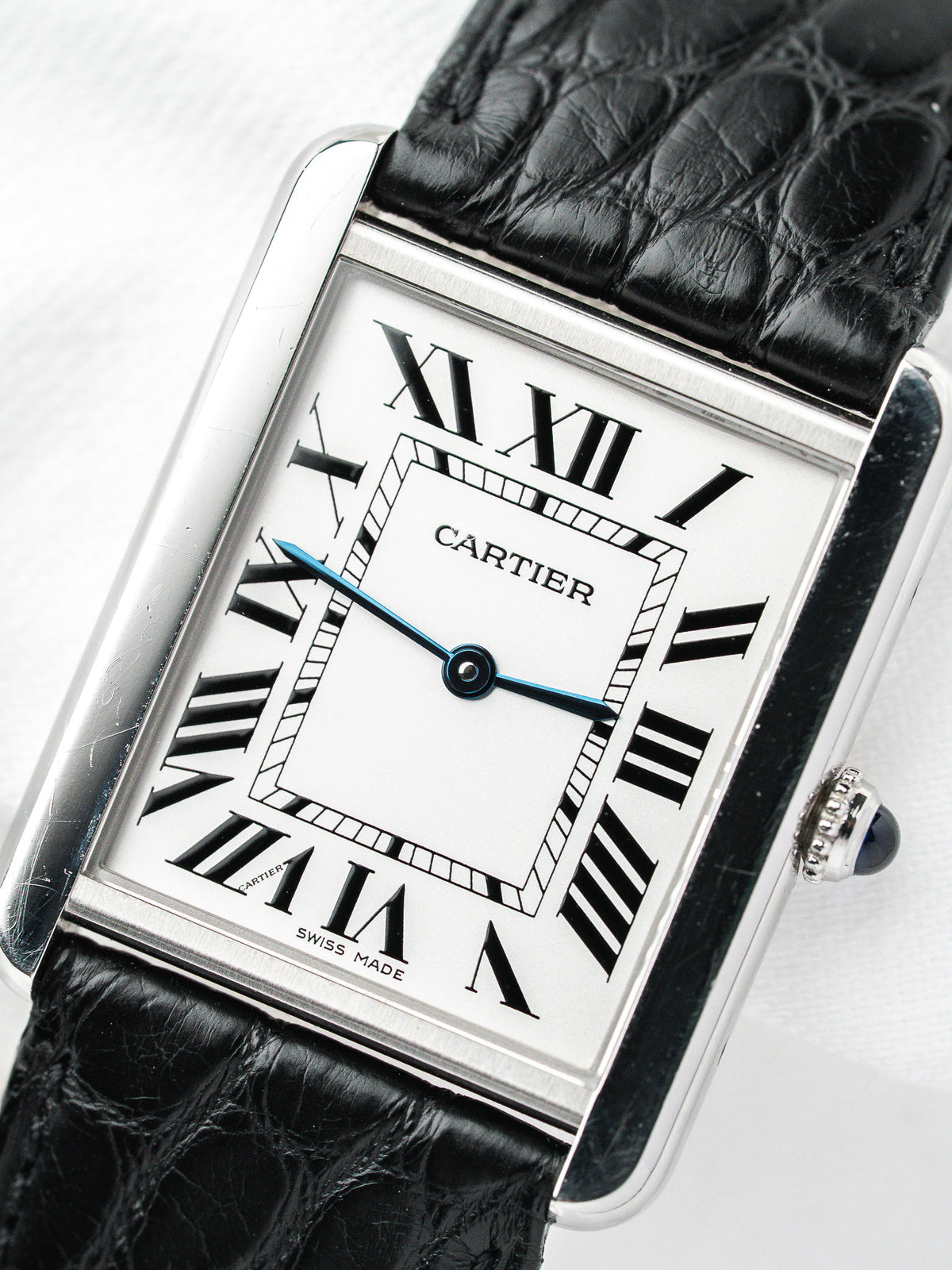 Montre Cartier Tank vintage, boîtier rectangulaire argenté, cadran blanc et bracelet cuir noir