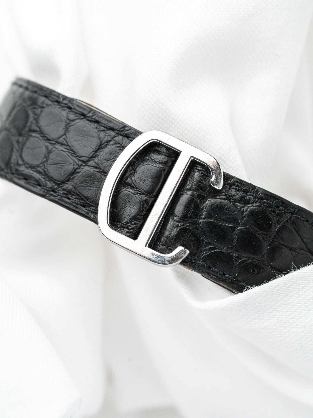 Bracelet de montre en cuir noir effet crocodile avec boucle argentée sur fond blanc