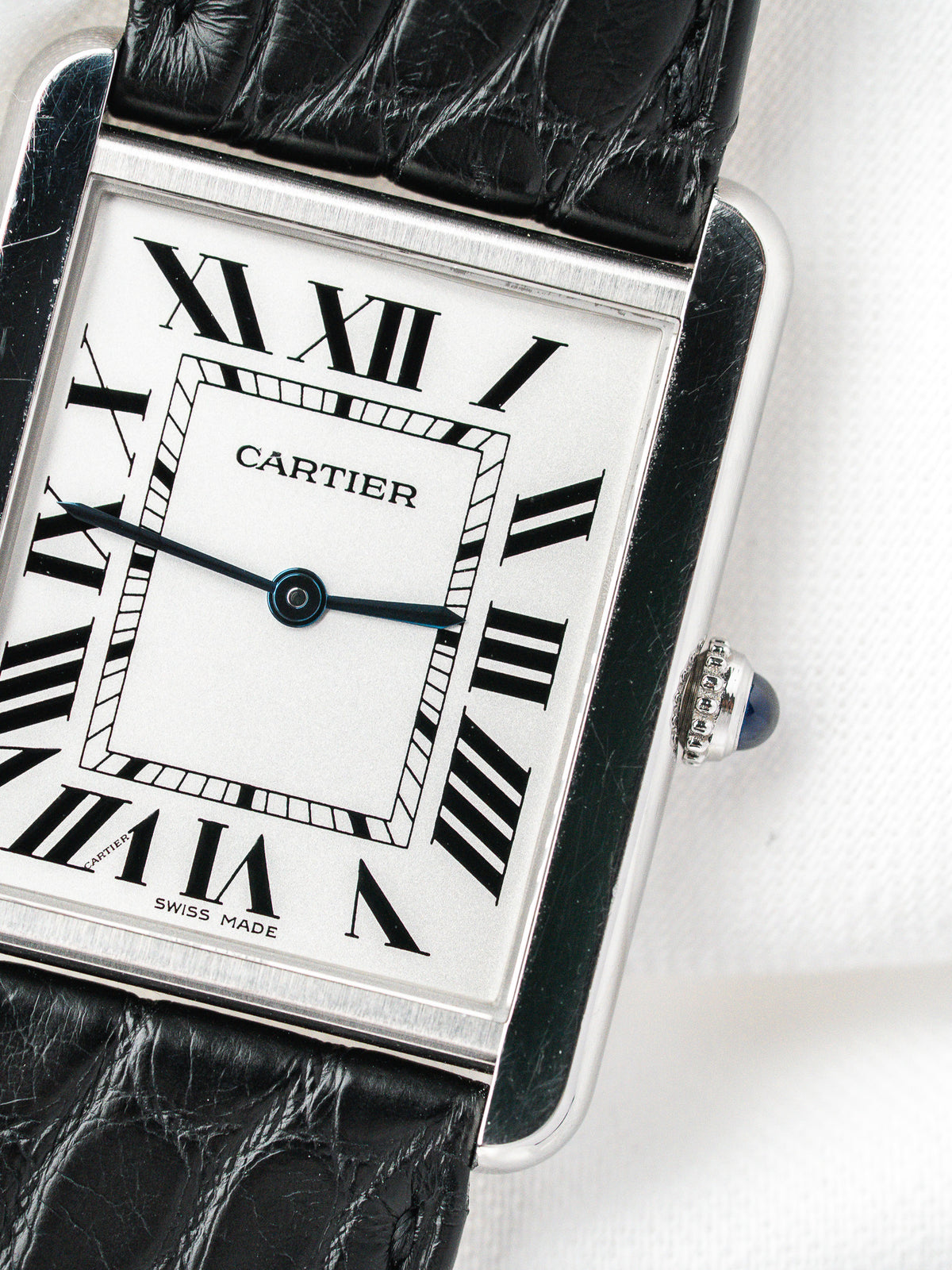 Montre Cartier Tank vintage, boîtier rectangulaire argenté, cadran blanc et bracelet cuir noir