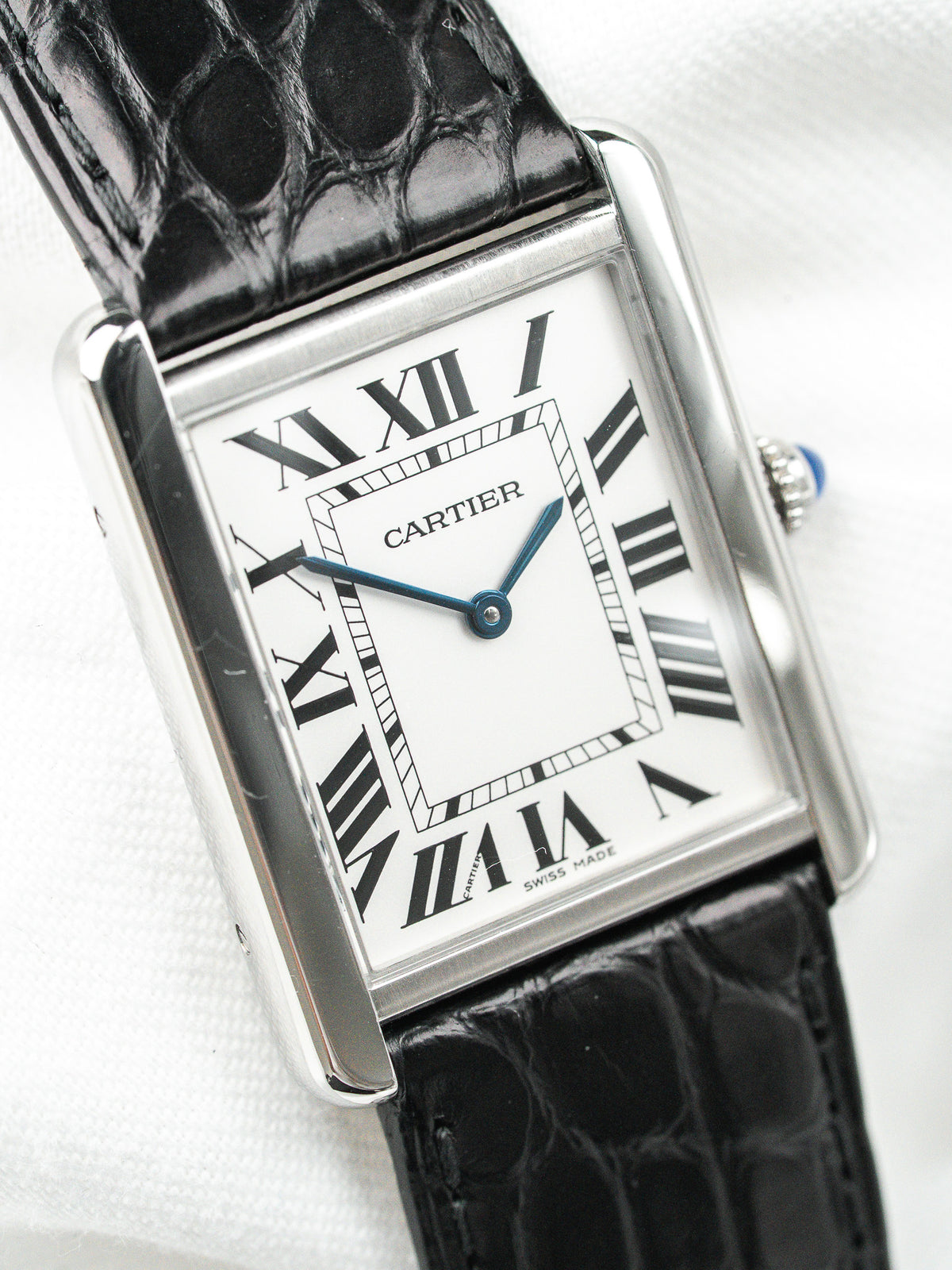 Montre Cartier Tank vintage, boîtier rectangulaire argenté, cadran blanc et bracelet cuir noir