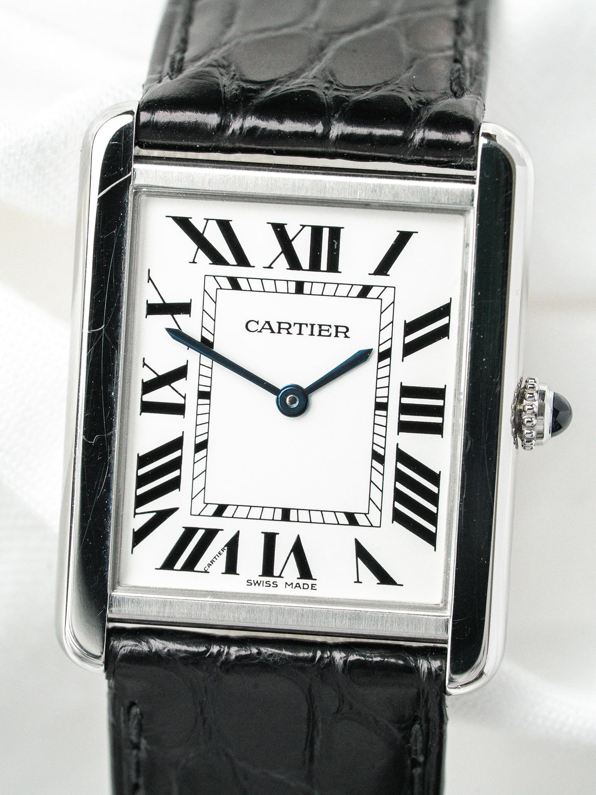 Montre Cartier Tank vintage, boîtier rectangulaire argenté, cadran blanc et bracelet cuir noir