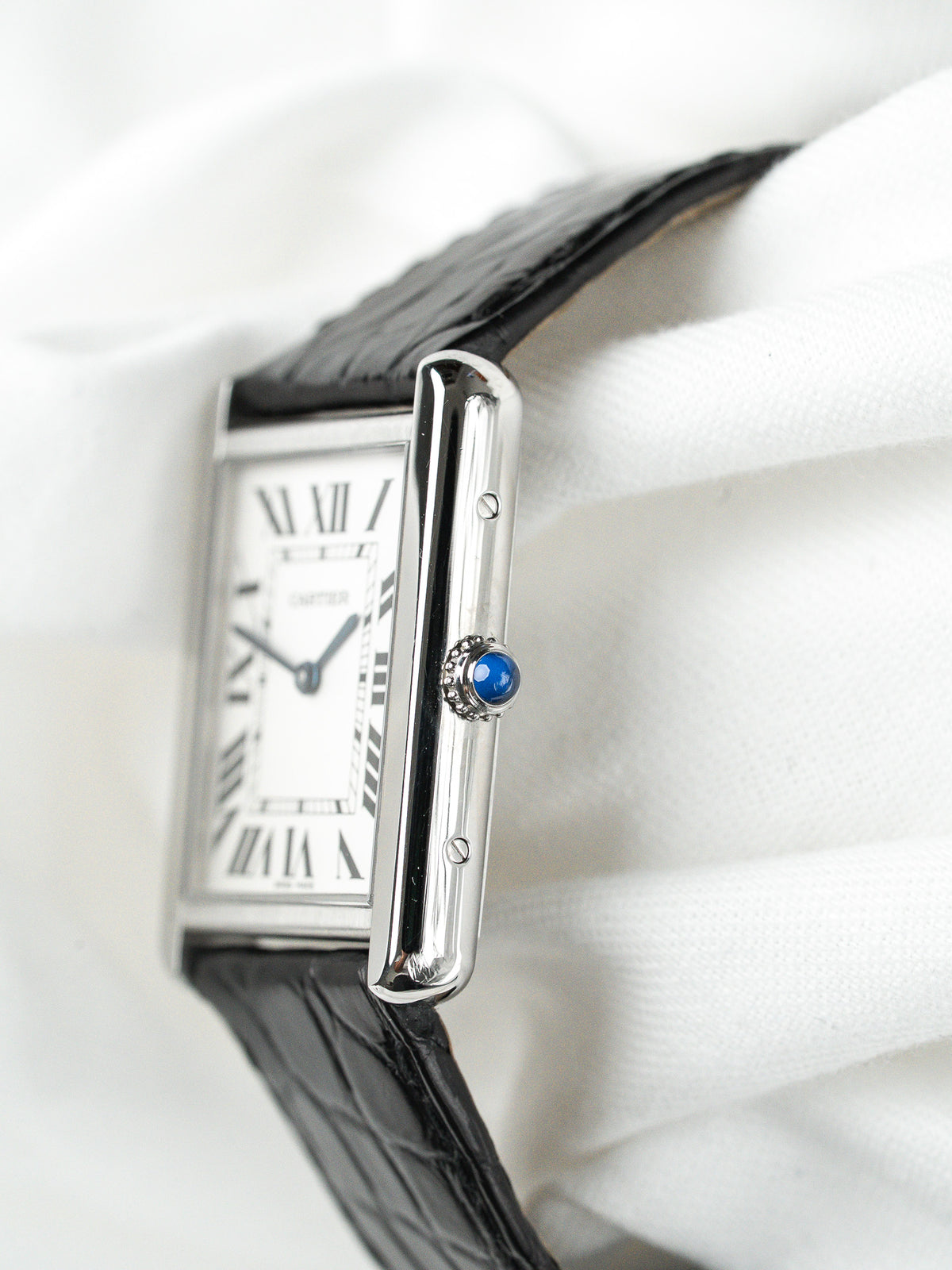 Montre Cartier Tank vintage, boîtier rectangulaire argenté, cadran blanc et bracelet cuir noir