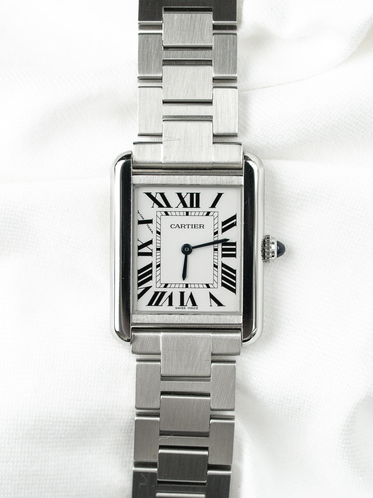 Montre Cartier Tank vintage en acier, boîtier rectangulaire, cadran blanc sur fond neutre